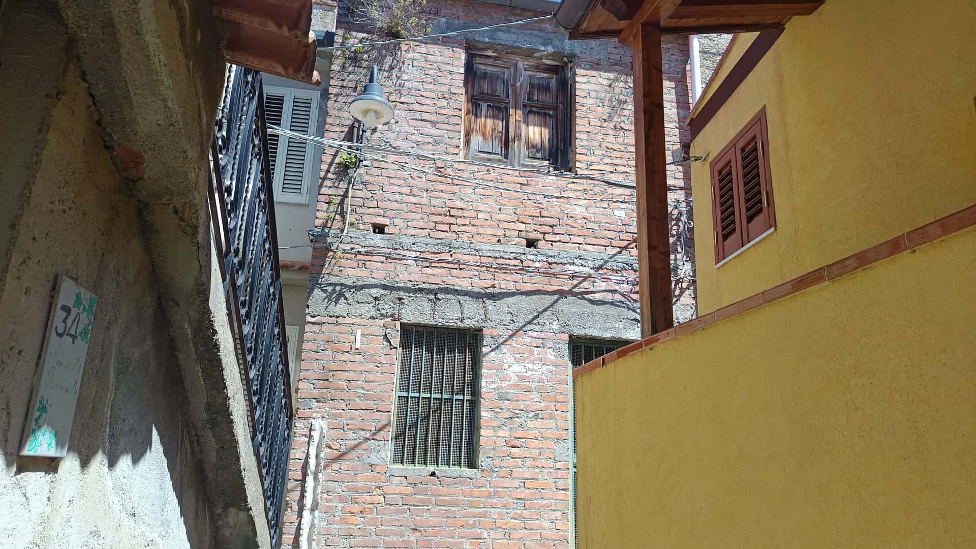 Pannello di case storiche con pareti in mattoni e finestre, in un quartiere urbano di città italiane, con dettagli architettonici tradizionali e un'atmosfera autentica.