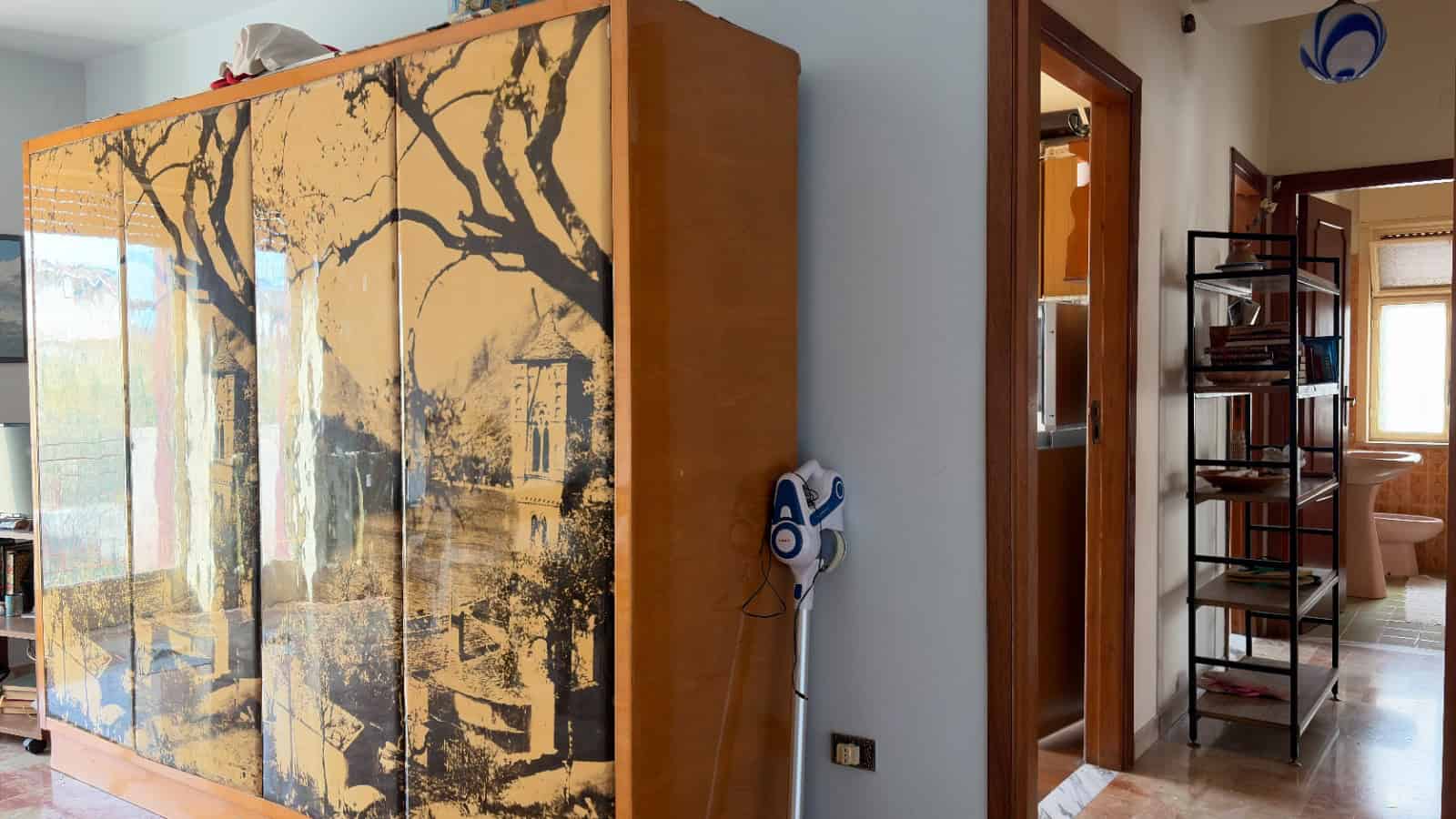 Armadio in legno con ante decorate con un motivo di alberi stilizzati in stile giapponese, posizionato in un soggiorno luminoso.