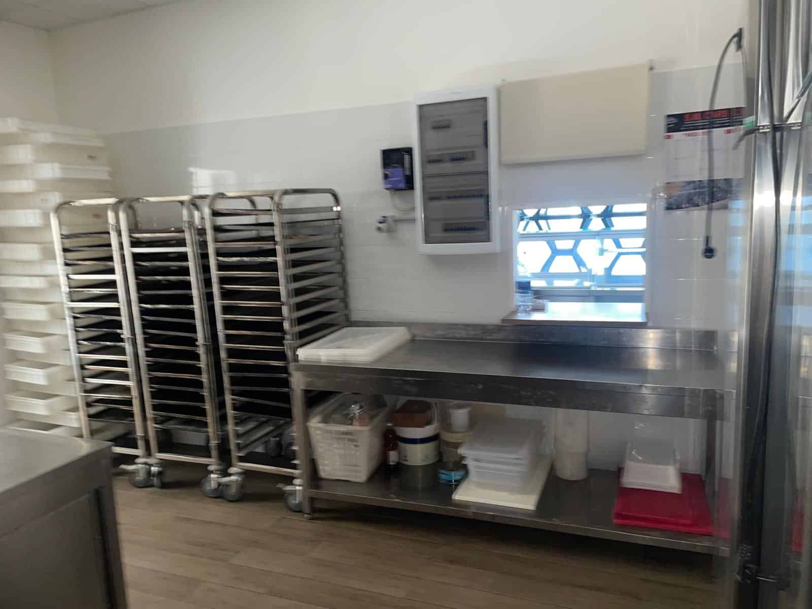 Lavanderia professionale con scaffali in acciaio, lavatrice industriale e area di lavoro ben organizzata, ideale per servizi di pulizia e gestione tessuti in strutture commerciali o alberghiere.