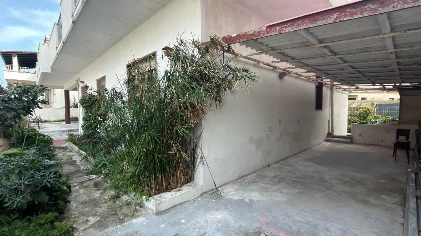 Immagine di un'area esterna di un edificio residenziale con piante verdi e un'area coperta, ideale per spazi esterni e relax.