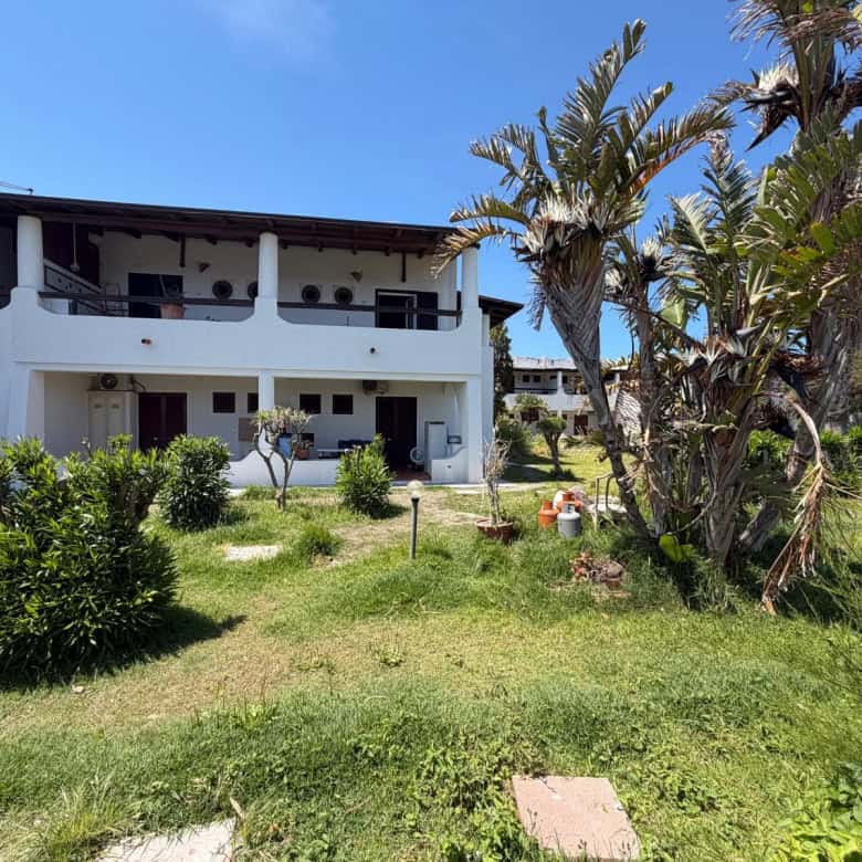 Villa moderna con ampio giardino e palme, ideale per vacanze rilassanti in Italia, vicino alle spiagge e ai servizi di NextCasa.
