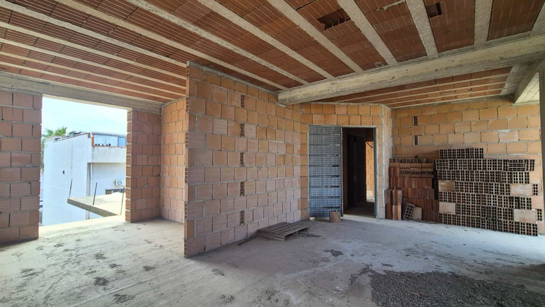 Pannello di costruzione in mattoni e cemento in un edificio in fase di costruzione, vista interna con apertura verso l'esterno.