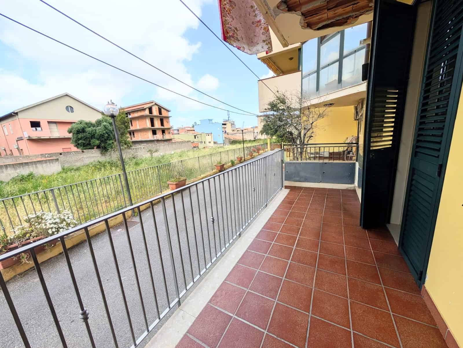 Balcone spazioso con pavimentazione in gres e vista su case e natura, ideale per relax e momenti all'aperto.