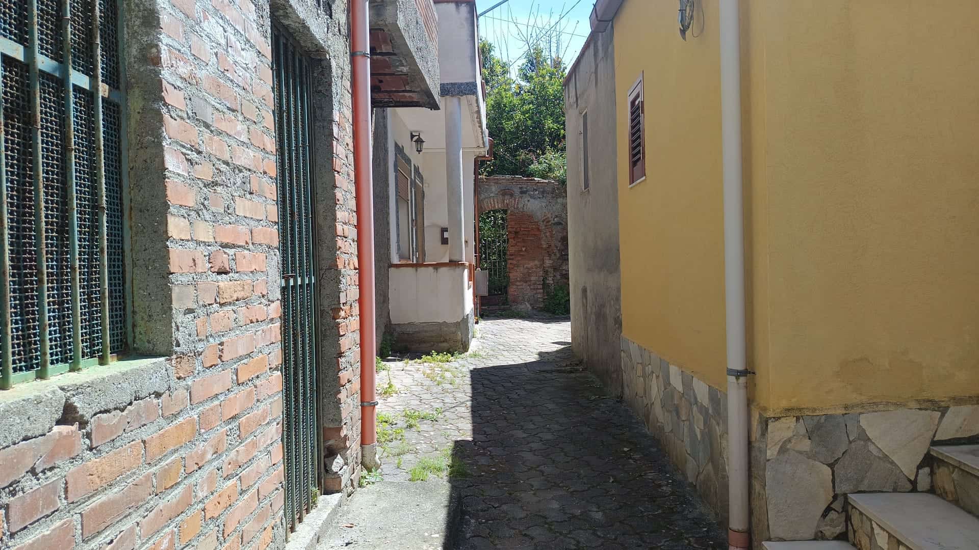 Vecchio vicolo di città con edifici in mattoni e pareti colorate, strada acciottolata e atmosfera storica.