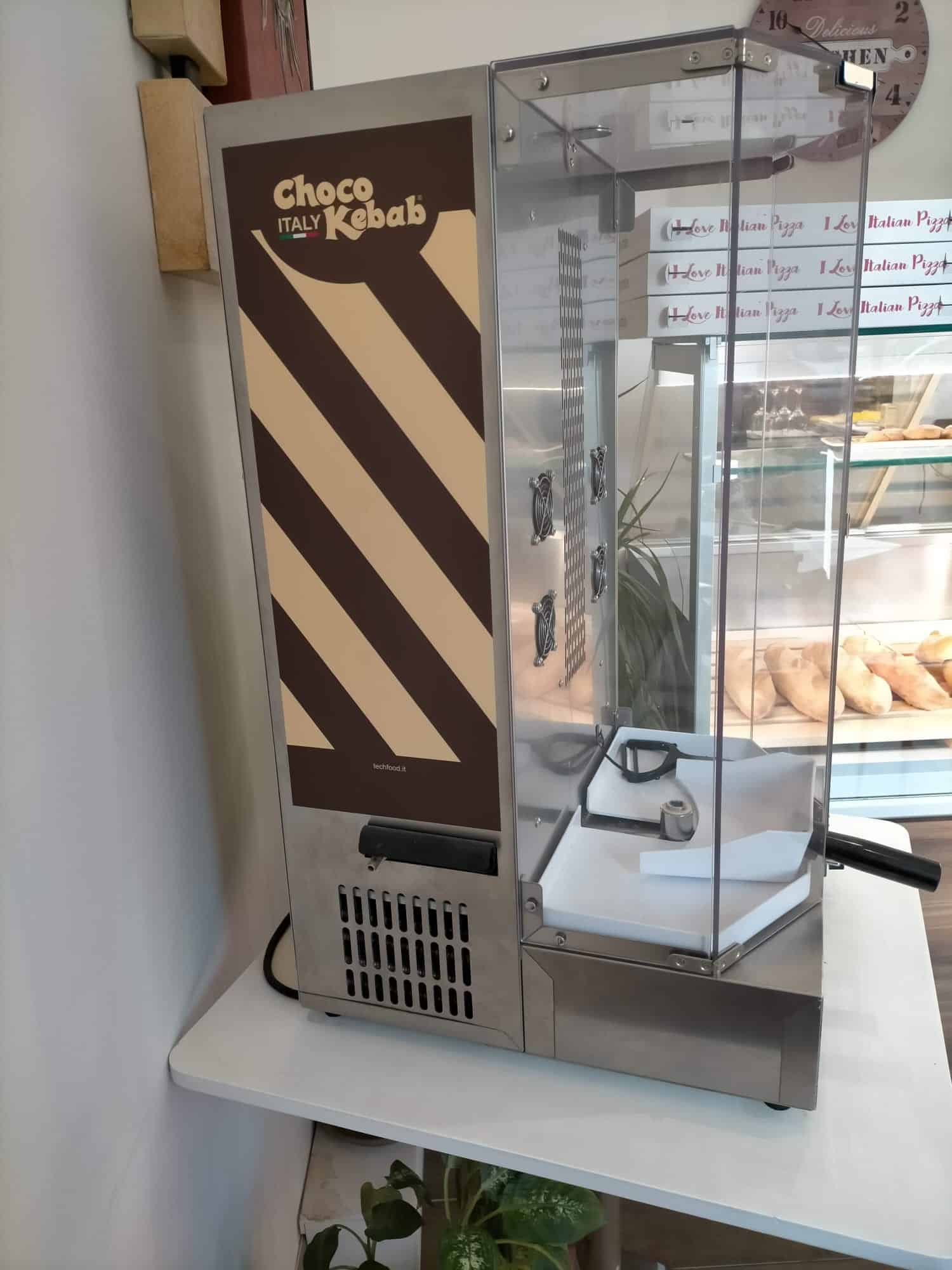 Un'asta di choco kebab automatizzata per la preparazione di snack dolci e salati, ideale per negozi e chioschi alimentari, con design moderno e funzionalità avanzate per un servizio rapido e efficient.