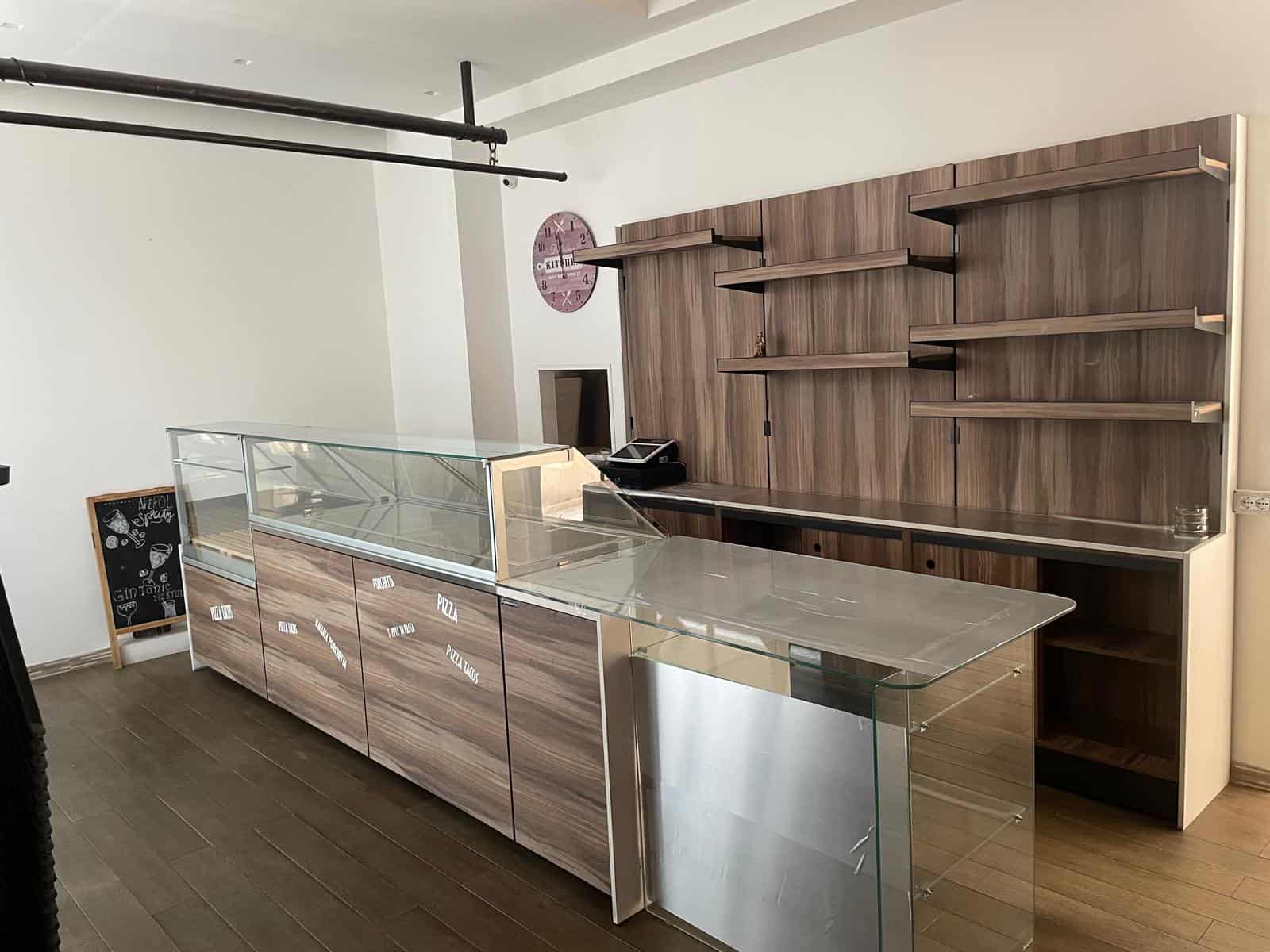 Il banco di vendita in vetro e legno con scaffalature moderne per negozi o uffici, ideale per esposizioni e spazi commerciali eleganti.