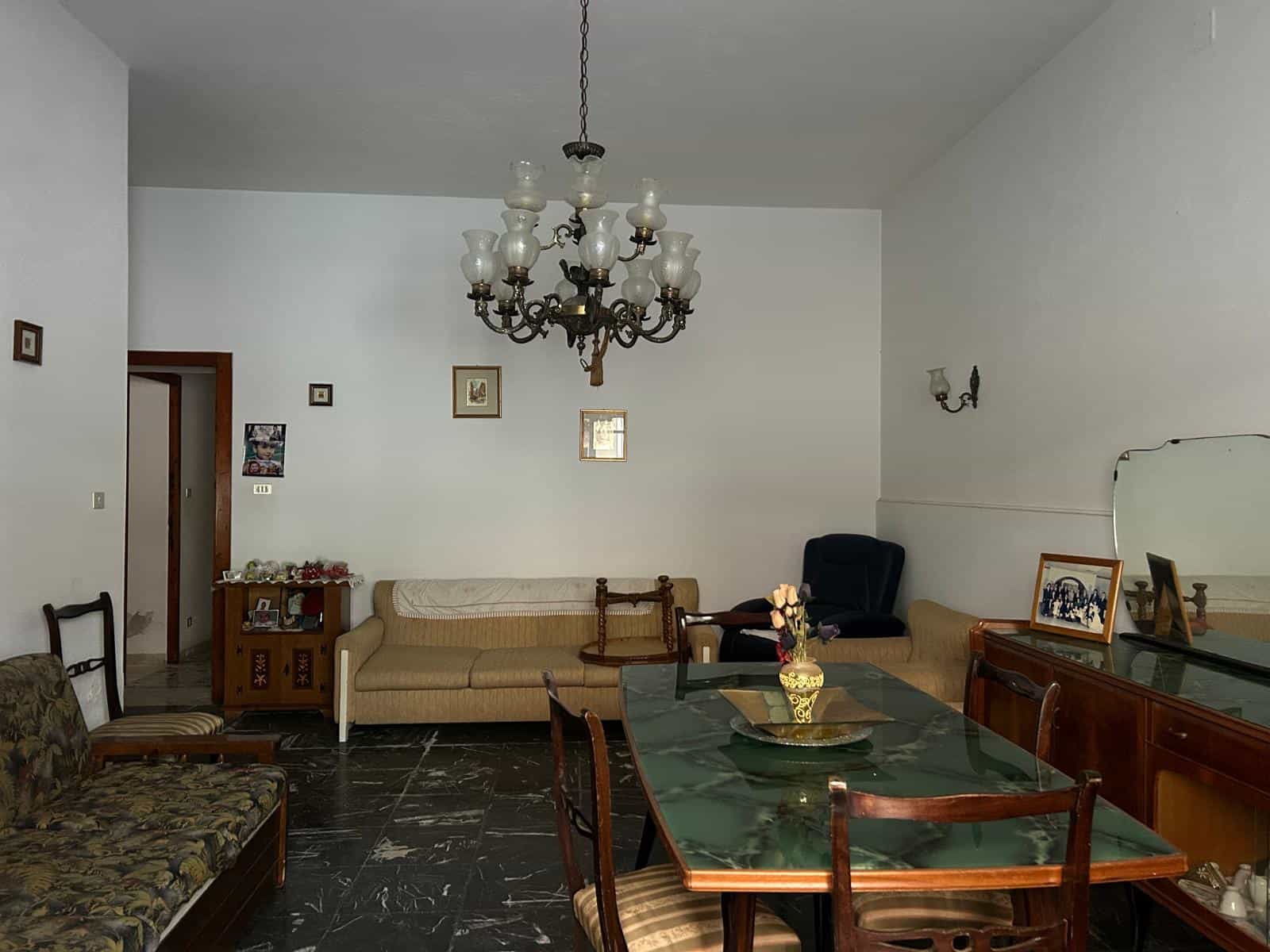 Sedie e divani in soggiorno classico con lampadario centrale e decorazioni vintage.
