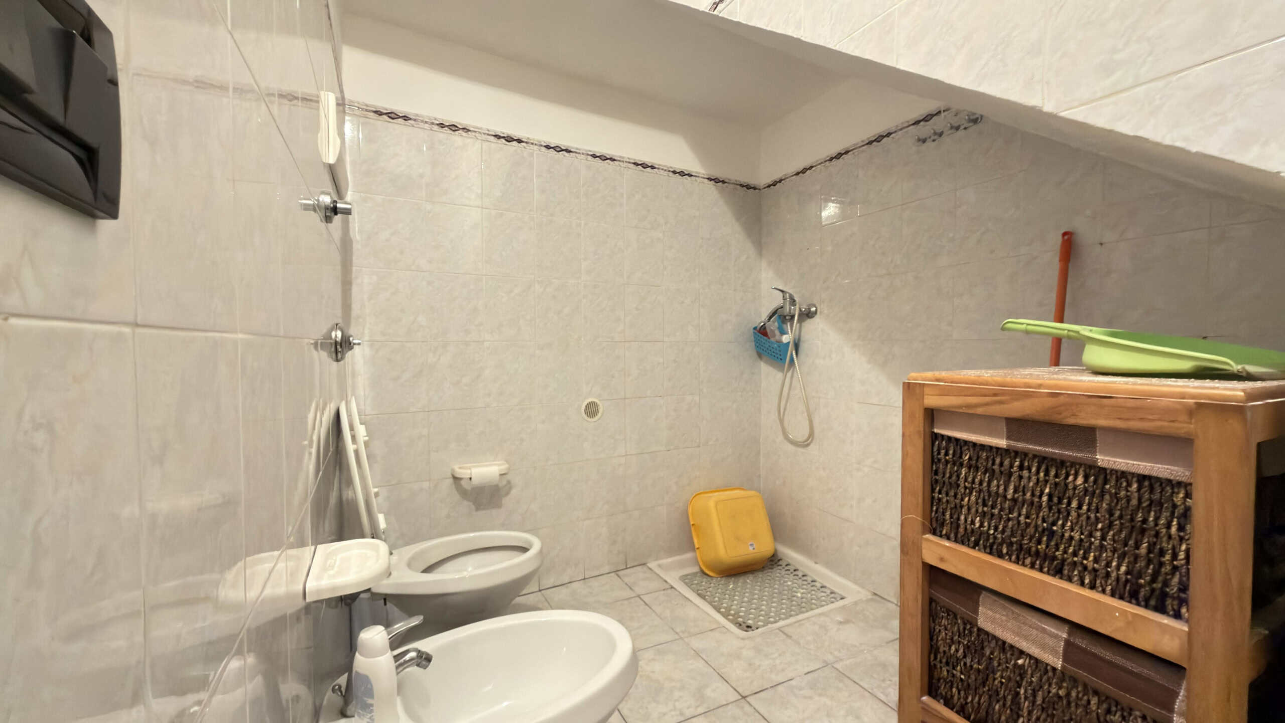 Spiaggia di bagno con doccia, lavabo e servizi igienici in un ambiente moderno e funzionale, ideale per strutture ricettive o spazi di relax. Design semplice e pratico con accessori essenziali.