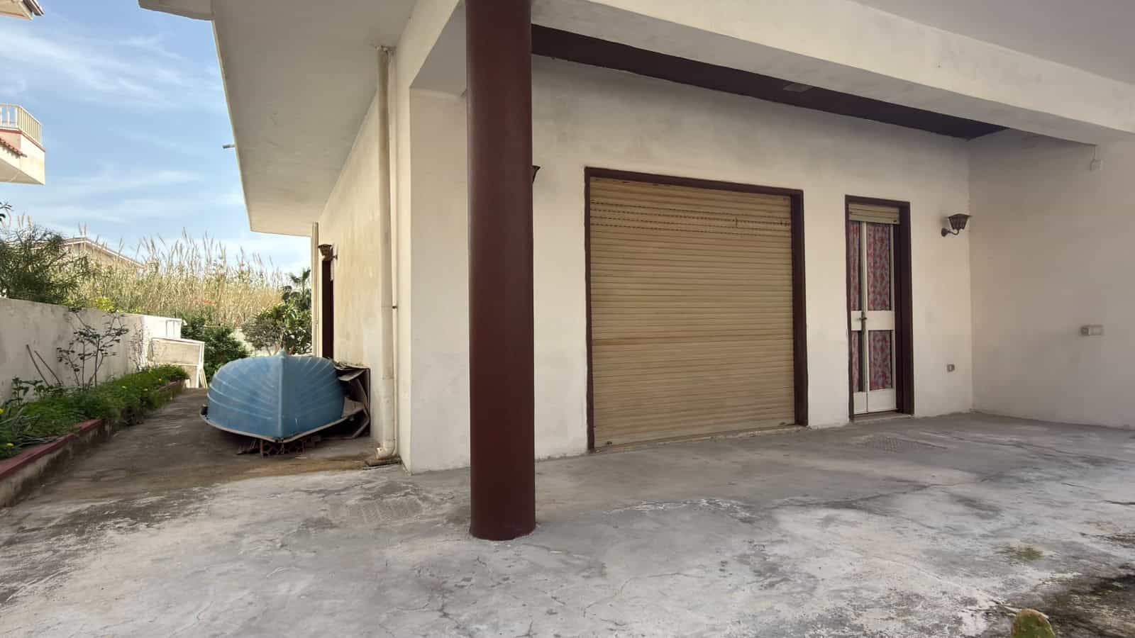 Ampio garage con porta sezionale e spazio esterno pavimentato, ideale per parcheggio e deposito, in zona residenziale tranquilla vicino a servizi e aree verdi.