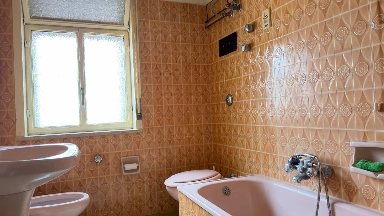Doccia e vasca da bagno in un bagno vintage con piastrelle arancioni, finestra luminosa e accessori bagno classici, ideale per una ristrutturazione o un progetto di interior design.