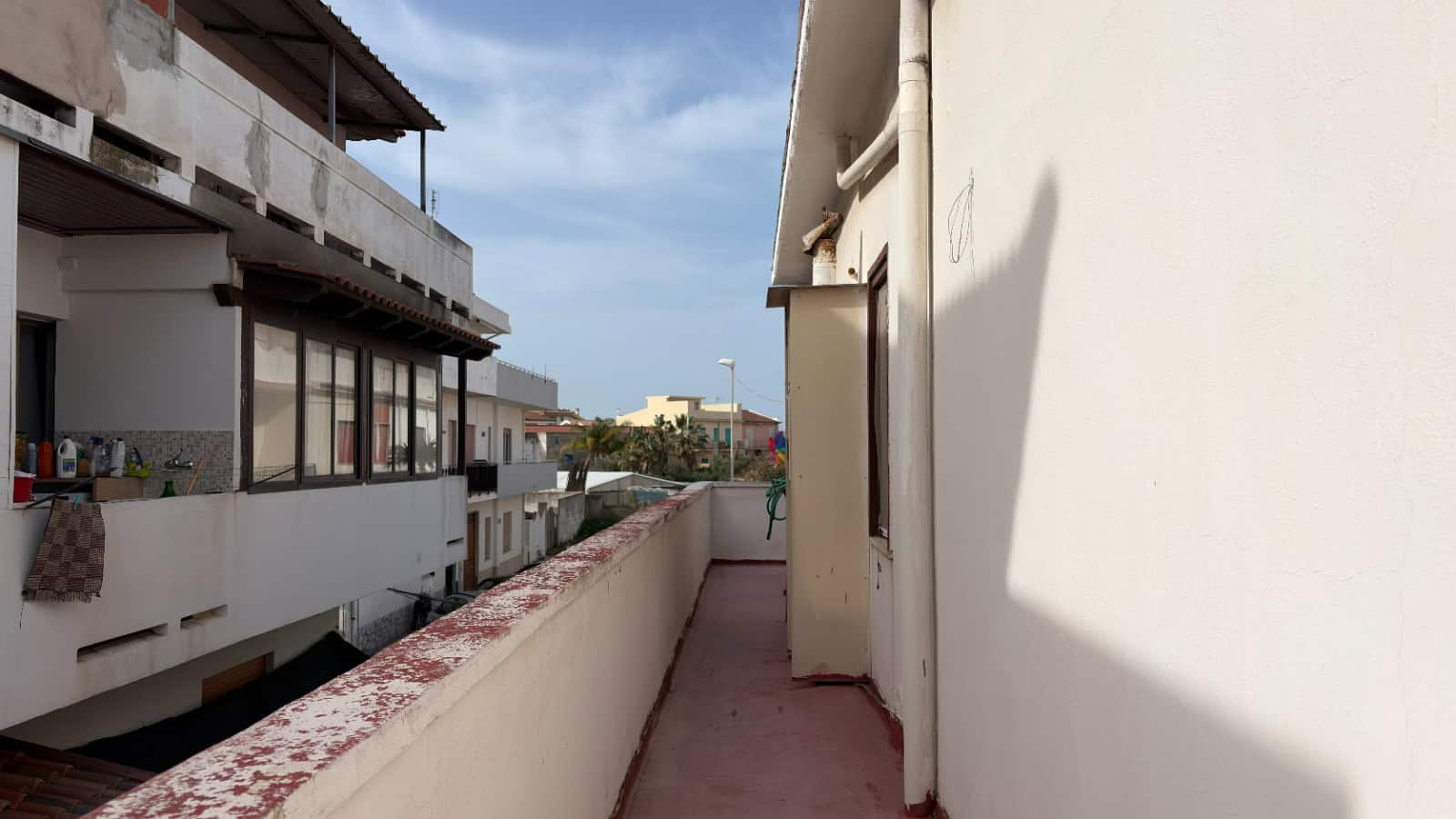 Balcone di un appartamento con vista su edifici residenziali e cielo sereno, ideale per relax e momenti all'aperto in zona urbana.