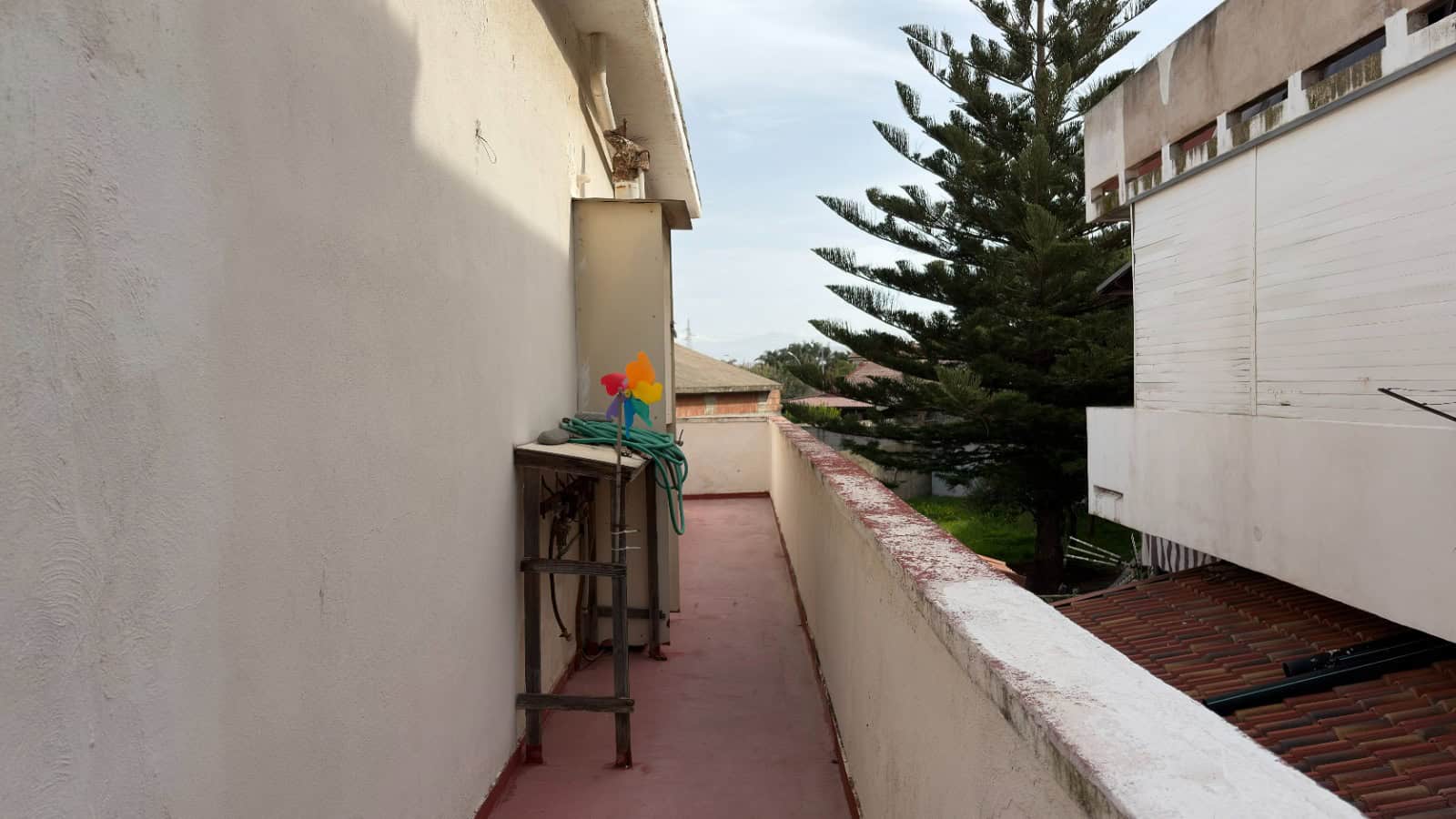 Balcone di un appartamento con vista su alberi e edifici circostanti, spazio esterno per relax e svago, in zona urbana.