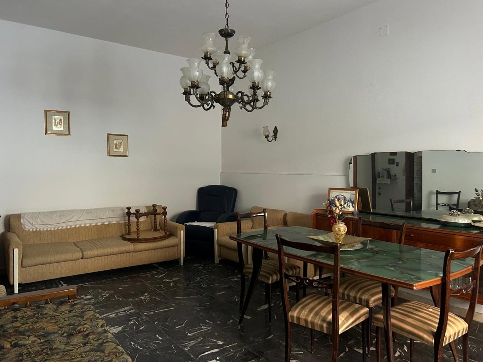 Elegante soggiorno con mobili classici, lampadario antico e pavimento in marmo nero, ideale per vivere momenti di relax e convivialità in un ambiente raffinato.