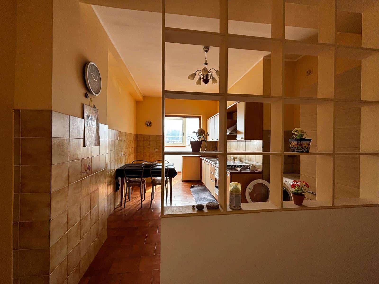 Cucina luminosa e accogliente con pareti gialle, mobili moderni e accessori decorativi, vista sulla finestra con luce naturale.