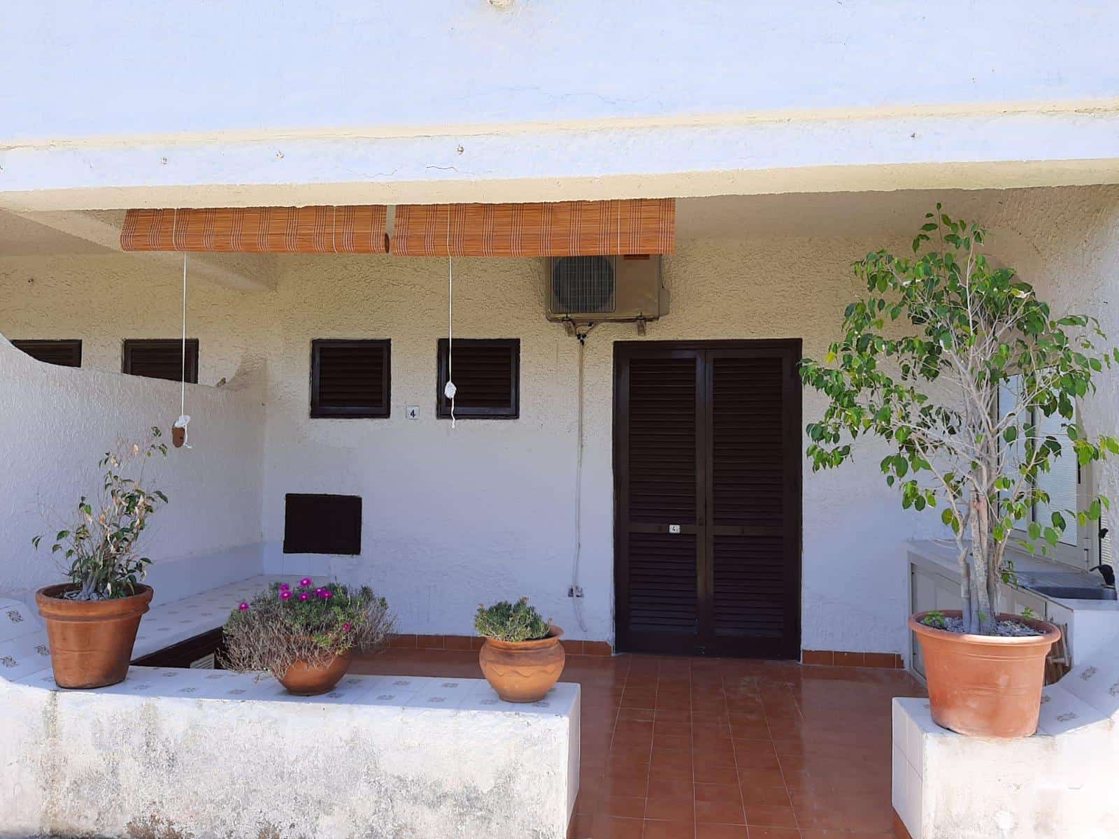 Vista di un'area esterna di una casa con piante in vaso e pareti bianche, ideale per ambienti di relax e convivialità.