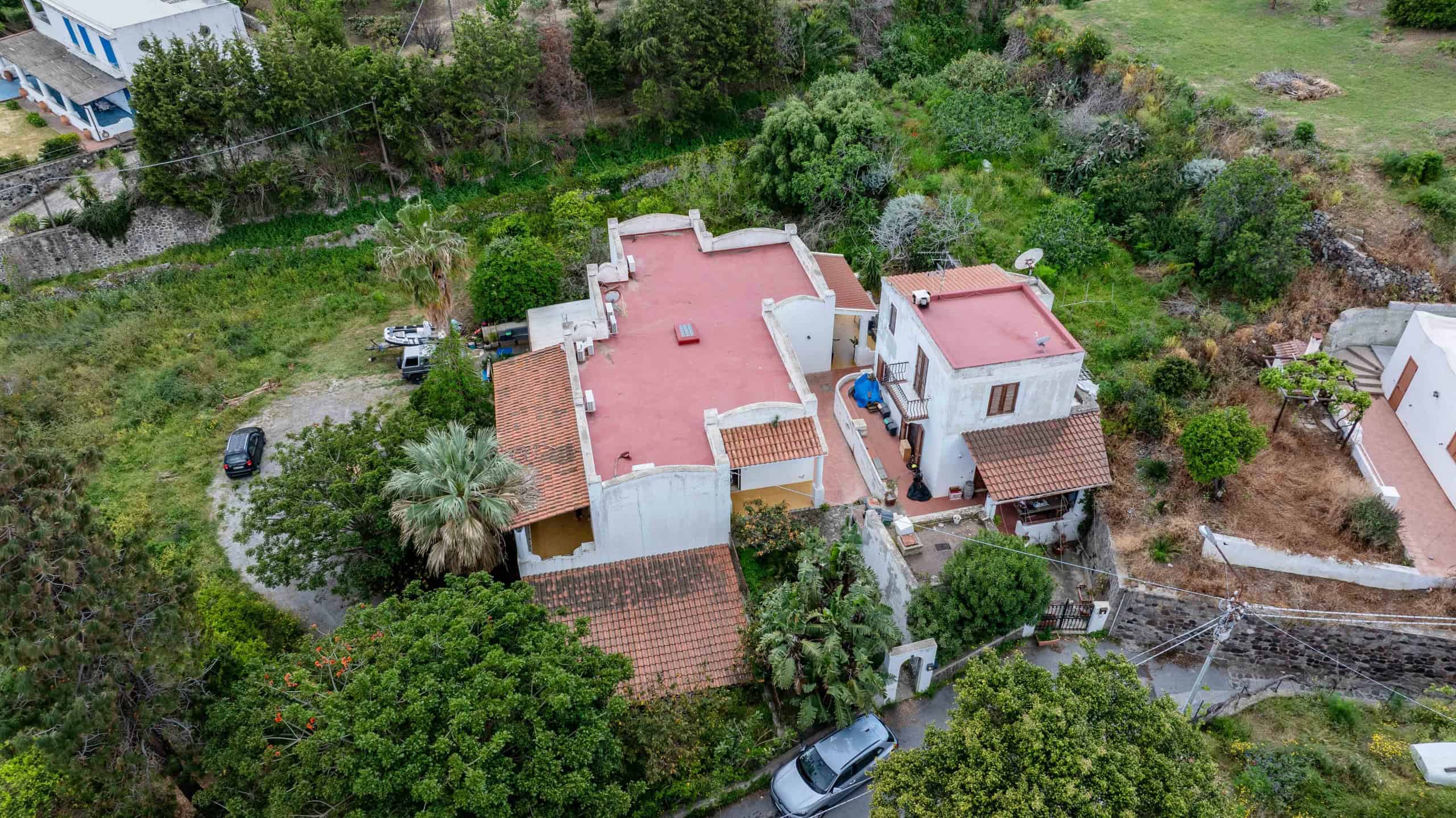 Vista aerea di una casa indipendente con giardino verde e strada privata, immersa in un'area tranquilla e ben curata, ideale per residenza familiare o investimento immobiliare.