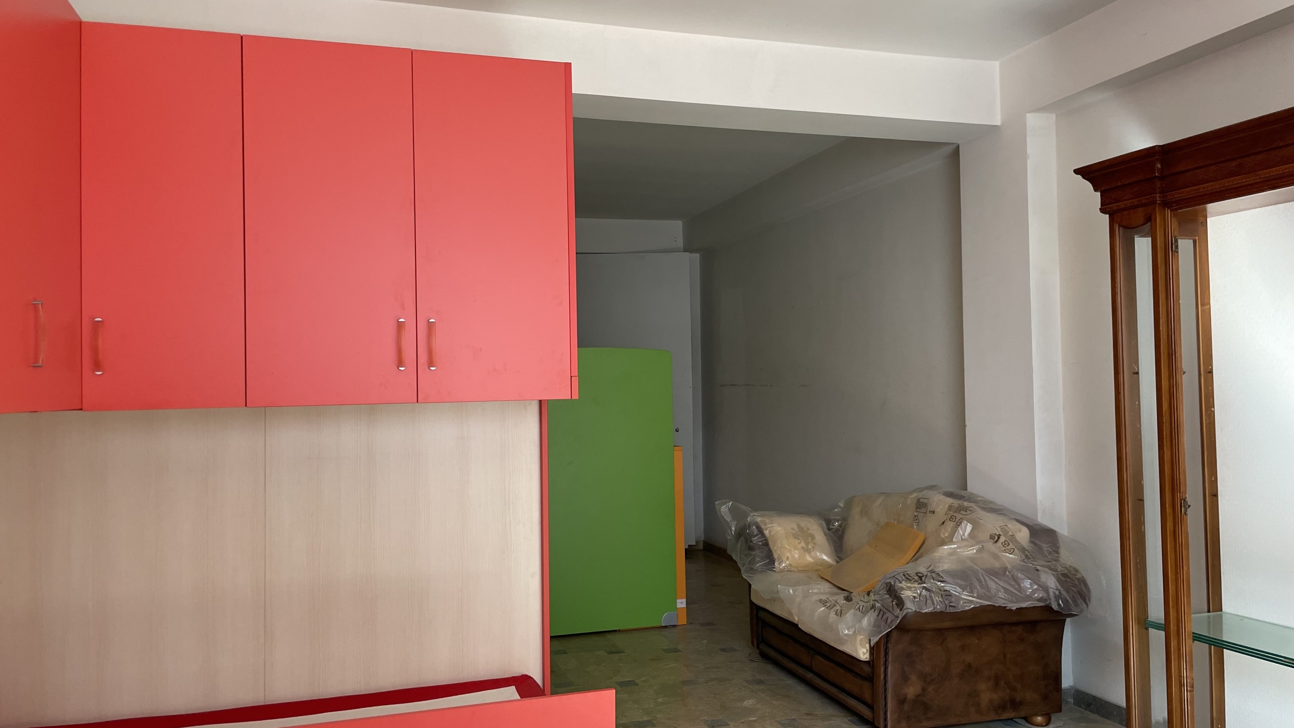 Armadio a muro colorato e soggiorno con divano in stile moderno, ambiente luminoso e accogliente, ideale per la vendita o l'affitto di immobili residenziali di qualità.
