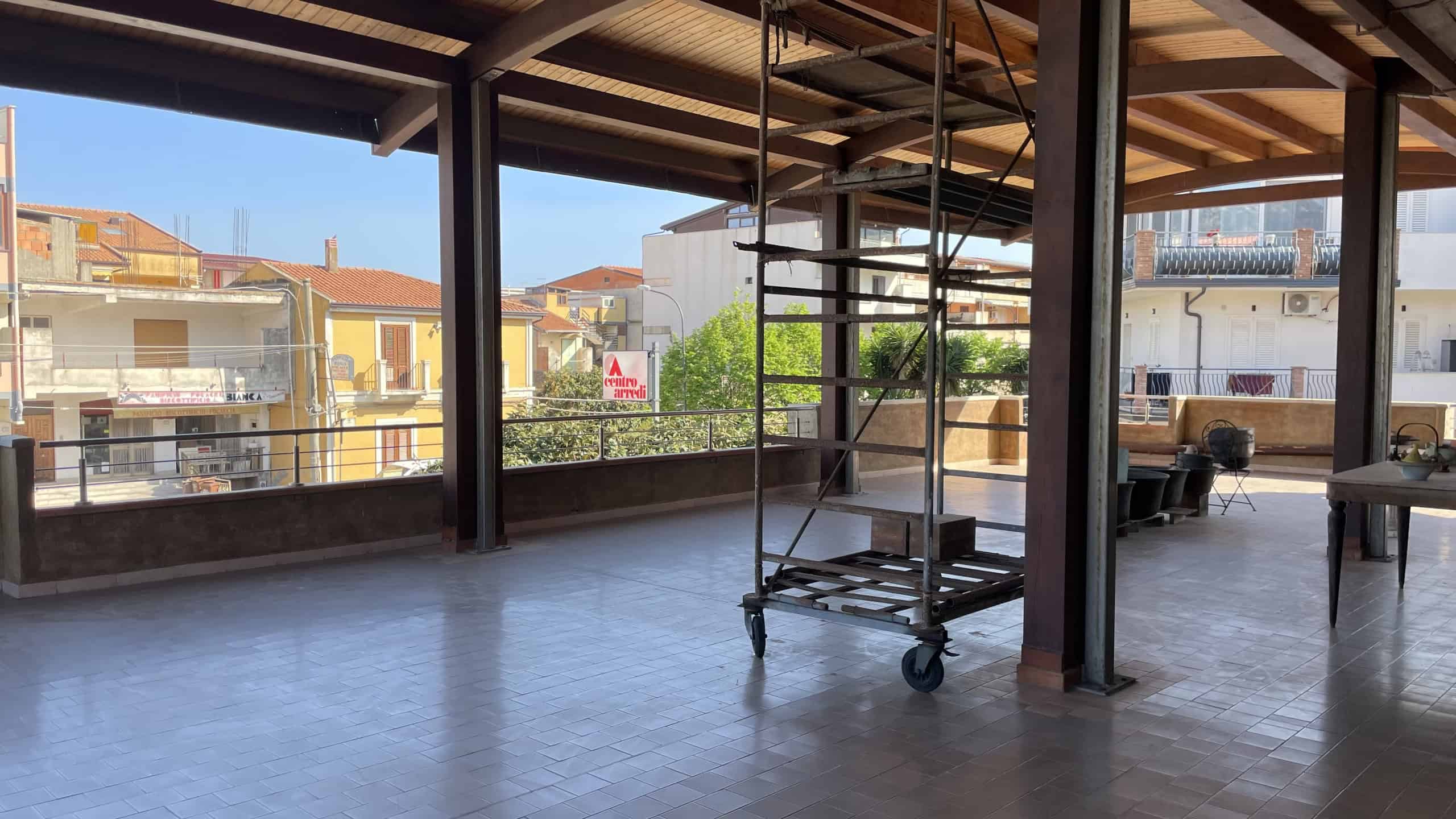 Piattaforma di lavoro su terrazza con vista su case colorate, struttura in metallo e pavimento in gres, ideale per ristrutturazioni e progetti di edilizia residenziale.