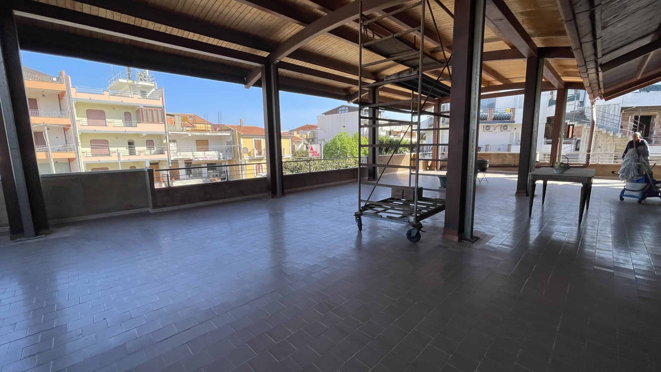 Piattaforma di lavoro su un balcone o terrazza con vista urbana, struttura in metallo e pavimento in piastrelle, spazio aperto e luminoso, ideale per ristrutturazioni o lavori di manutenzione edilizia.
