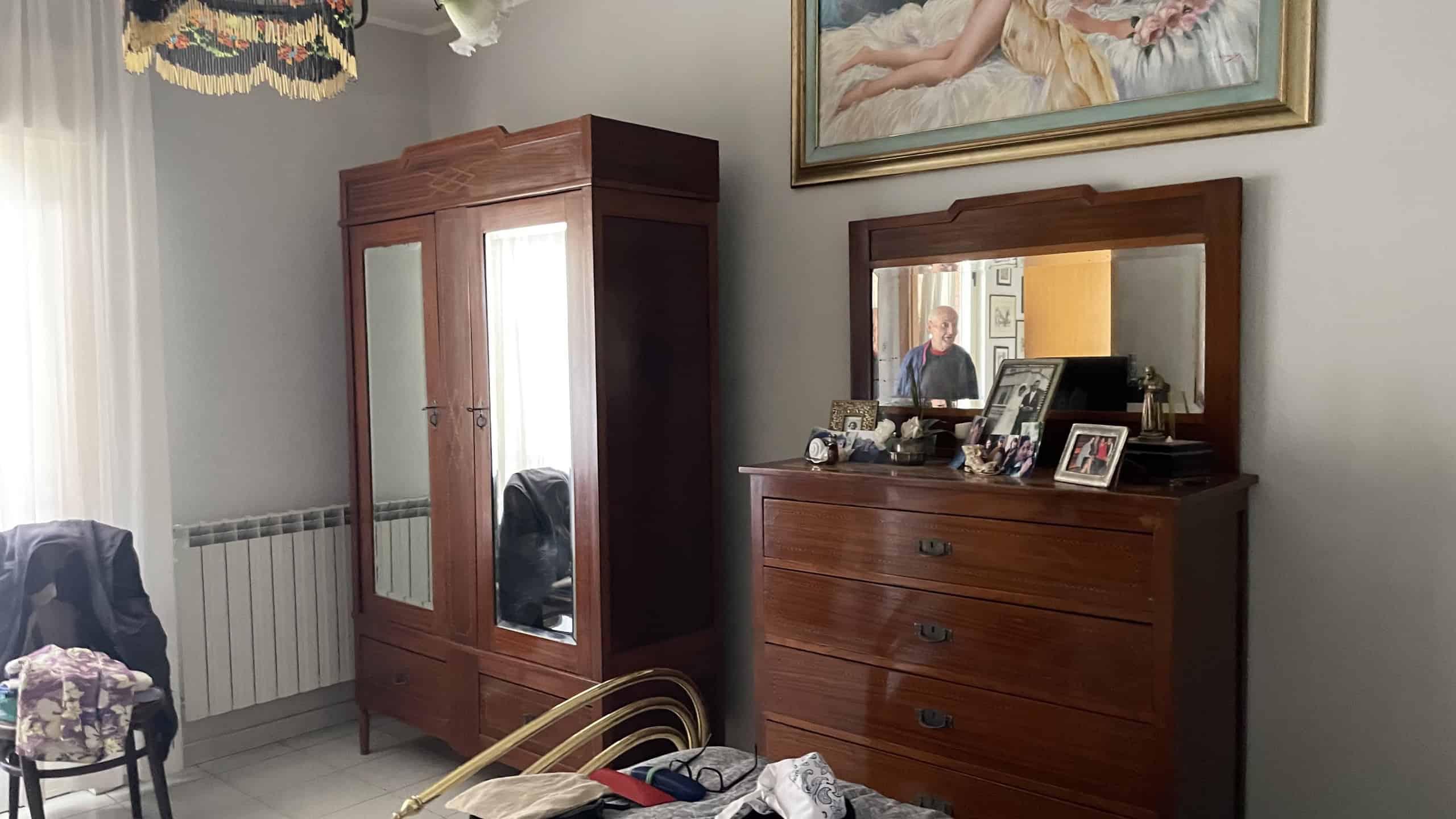 Armadio in legno antico con specchi e cassettiera in stile classico in una stanza luminosa.