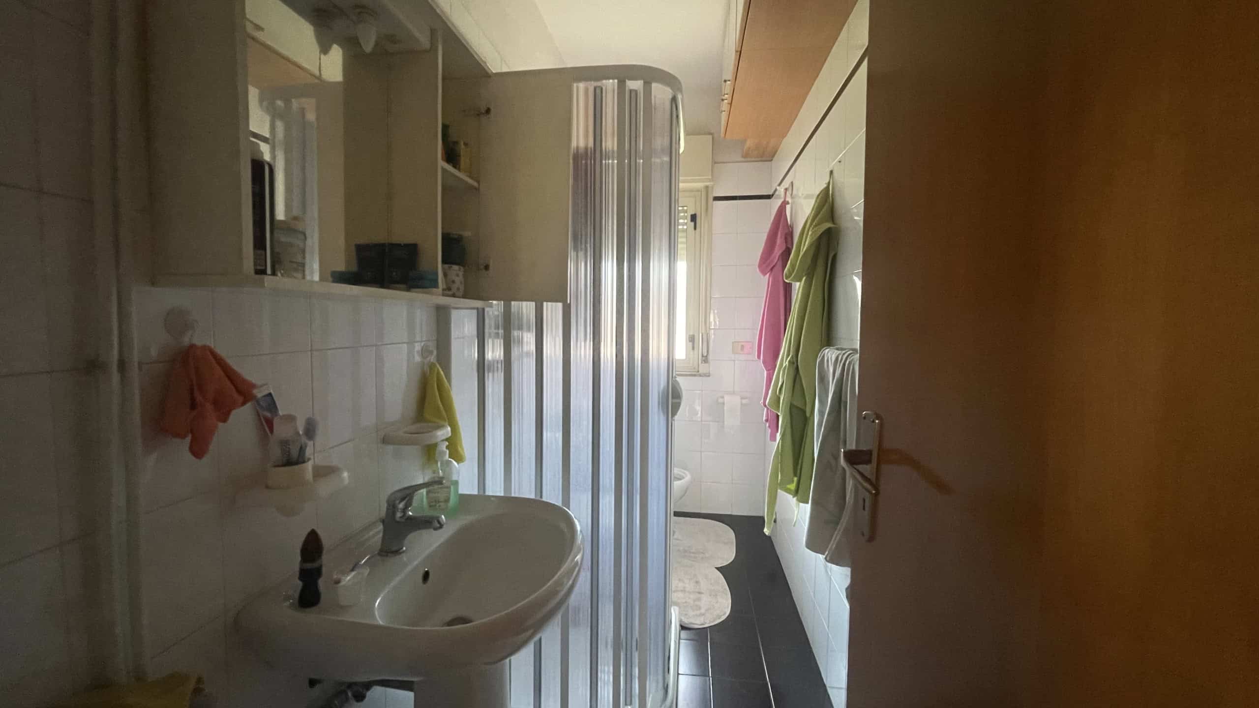 Lavabo e parete con asciugamani colorati in un bagno moderno e luminoso.