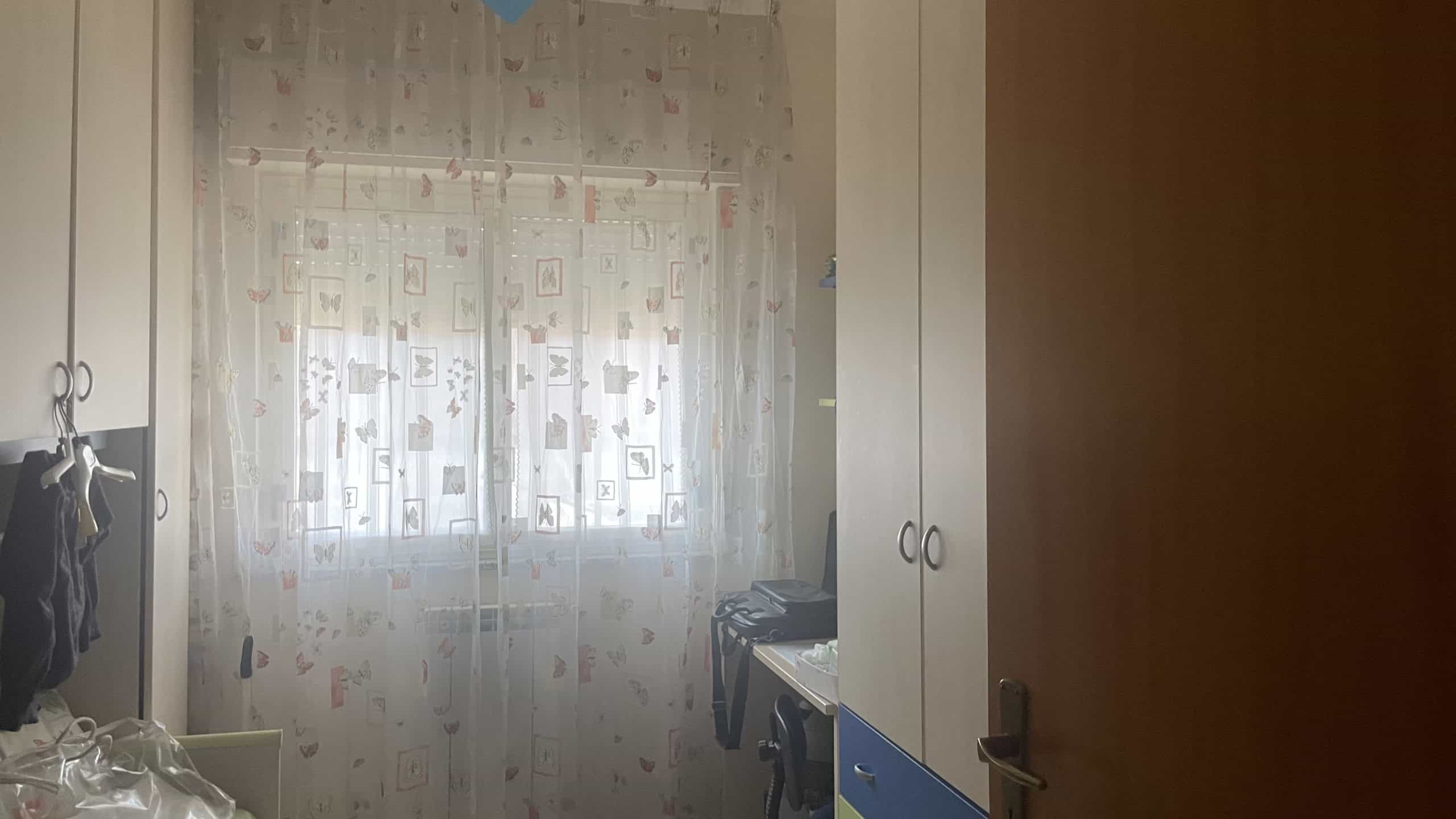 Ampio soggiorno con finestra luminosa, tende leggere e arredi moderni, ideale per vivere in comfort e stile.