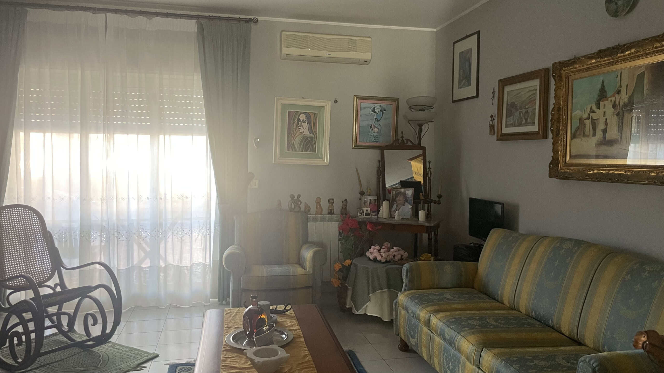 Soggiorno luminoso con divano, poltrona e decorazioni artistiche, ideale per relax e convivialità.