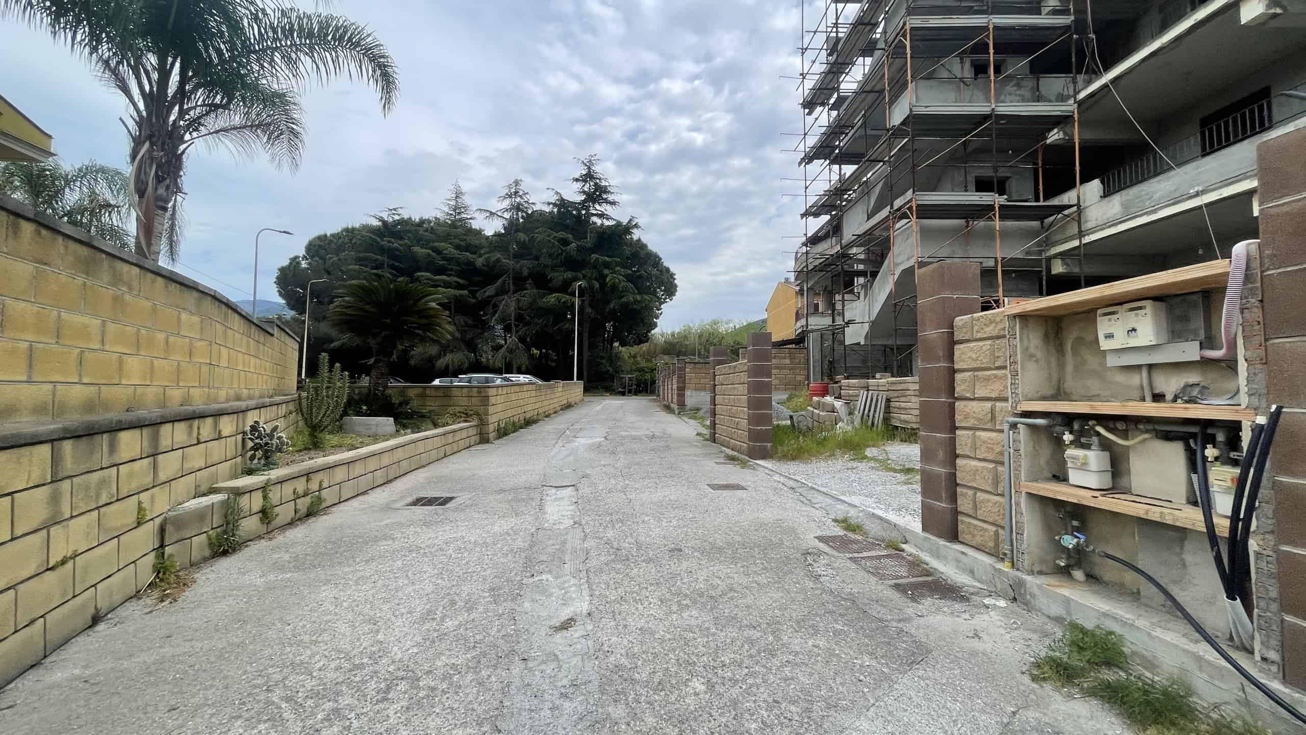 Ampio cantiere edilizio con strutture in costruzione e materiali di lavoro, strada asfaltata e ambiente urbano in fase di sviluppo, pronto per nuove costruzioni residenziali o commerciali.