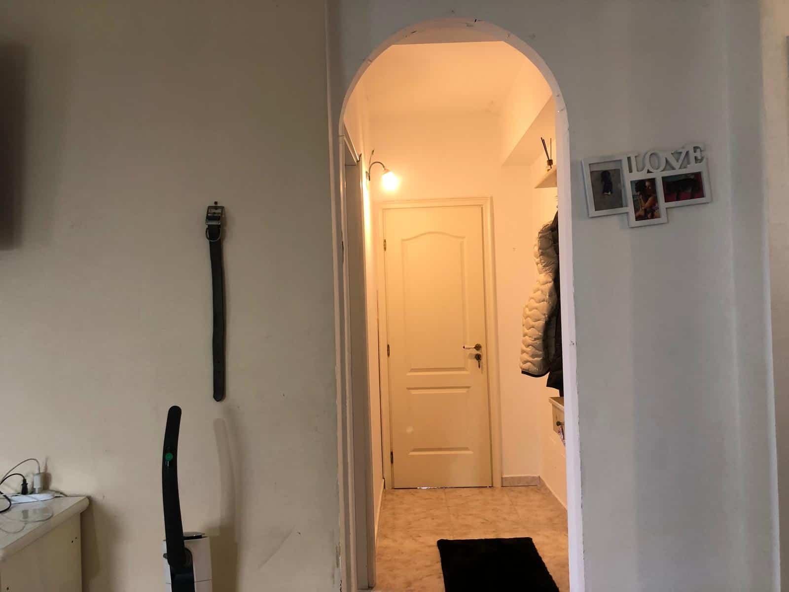 Entrata di casa con porta bianca, arredo semplice e illuminazione calda, ideale per appartamenti moderni e accoglienti.