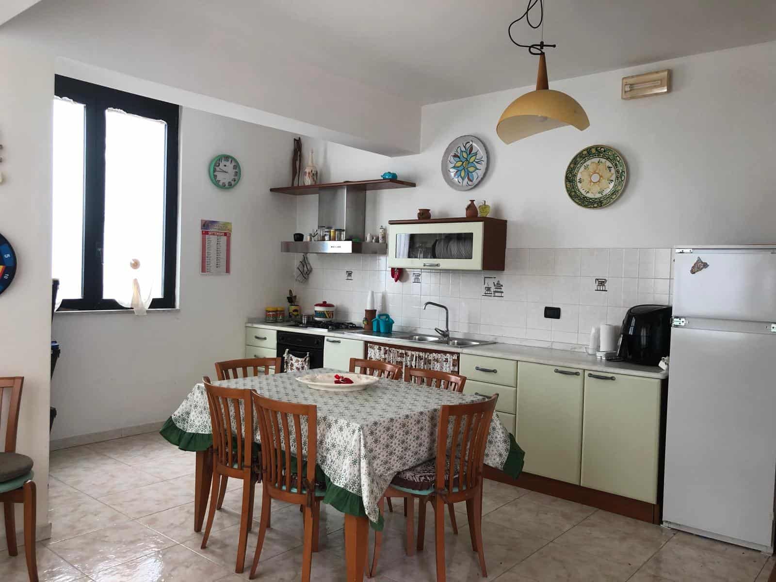 Panca cucina moderna con tavolo da pranzo in soggiorno luminoso, arredamento funzionale e decorazioni colorate, ideale per vivere momenti conviviali in famiglia.
