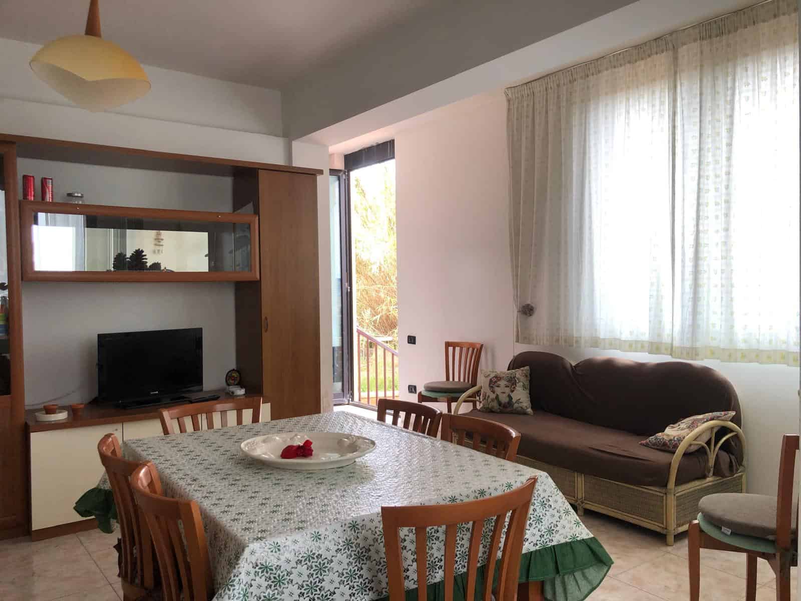 Ampio soggiorno con tavolo da pranzo, divano e TV, ambiente luminoso e accogliente, ideale per vivere momenti di relax e convivialità in una casa moderna e ben arredata.