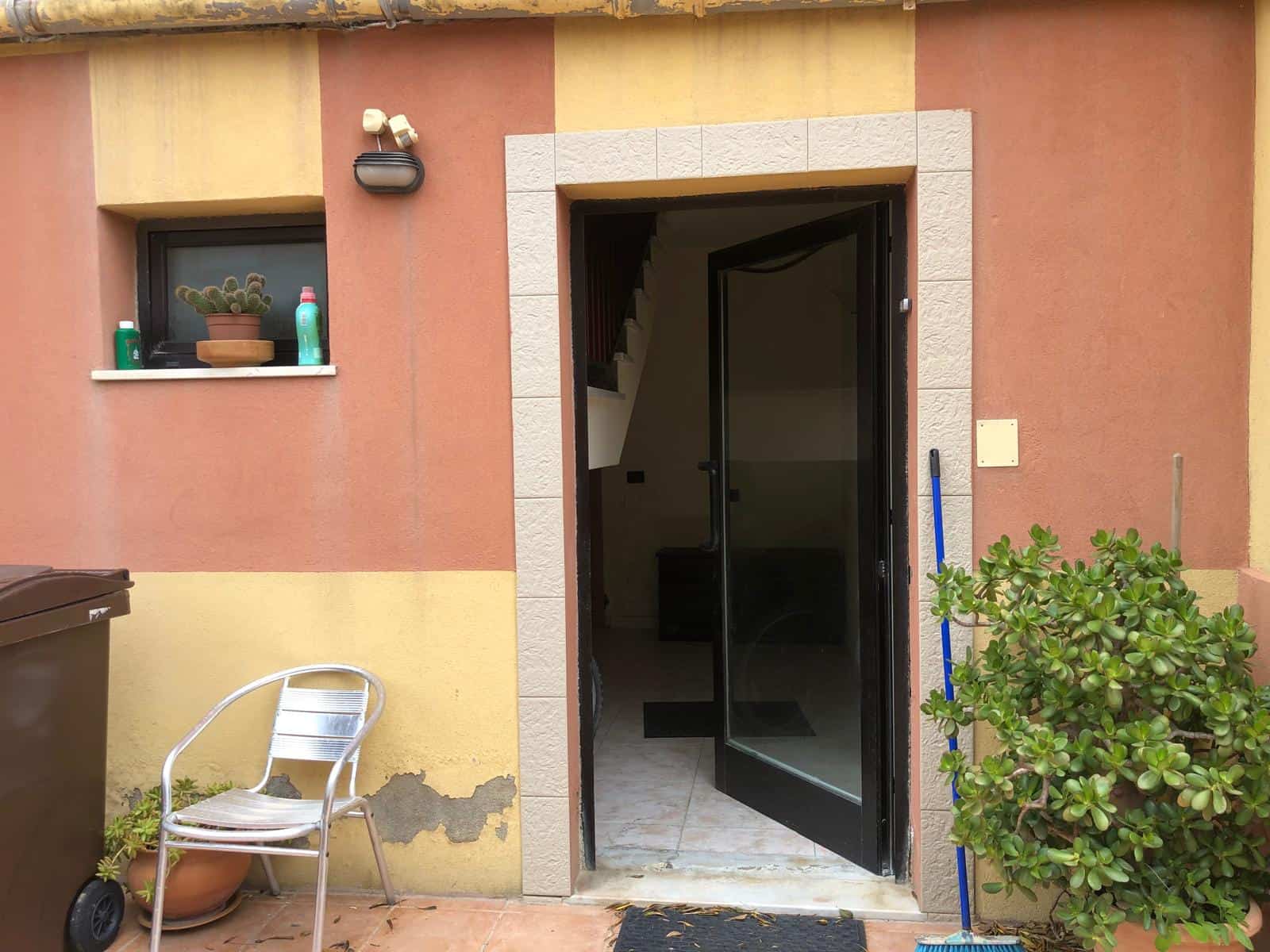 Entrata di casa con porta a vetri e giardino esterno, ambiente residenziale con piante e arredi da esterno.
