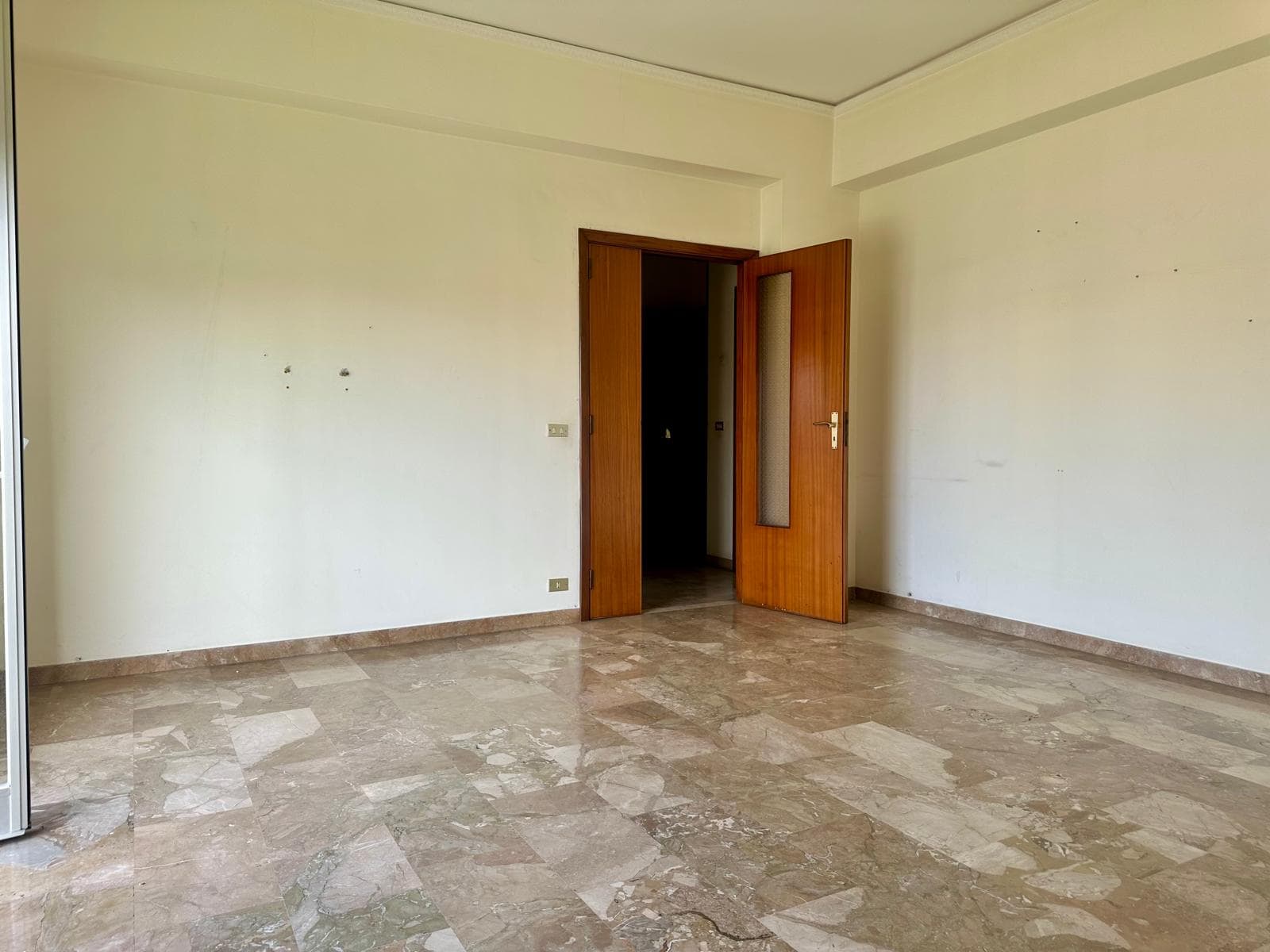 Aggiungi una porta aperta in una stanza vuota con pareti bianche e pavimento in marmo beige, ideale per annunci immobiliari e ristrutturazioni.