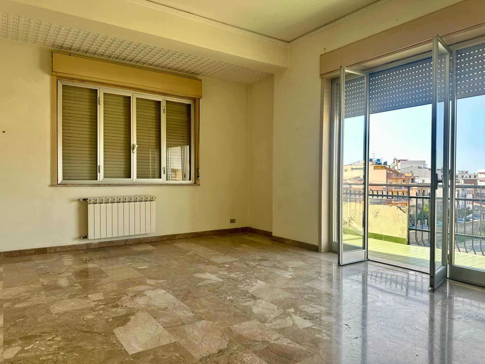 Ampio soggiorno con grandi finestre e balcone, luminoso e spazioso, ideale per vivere e rilassarsi, con vista sulla città e pavimento in marmo elegante.