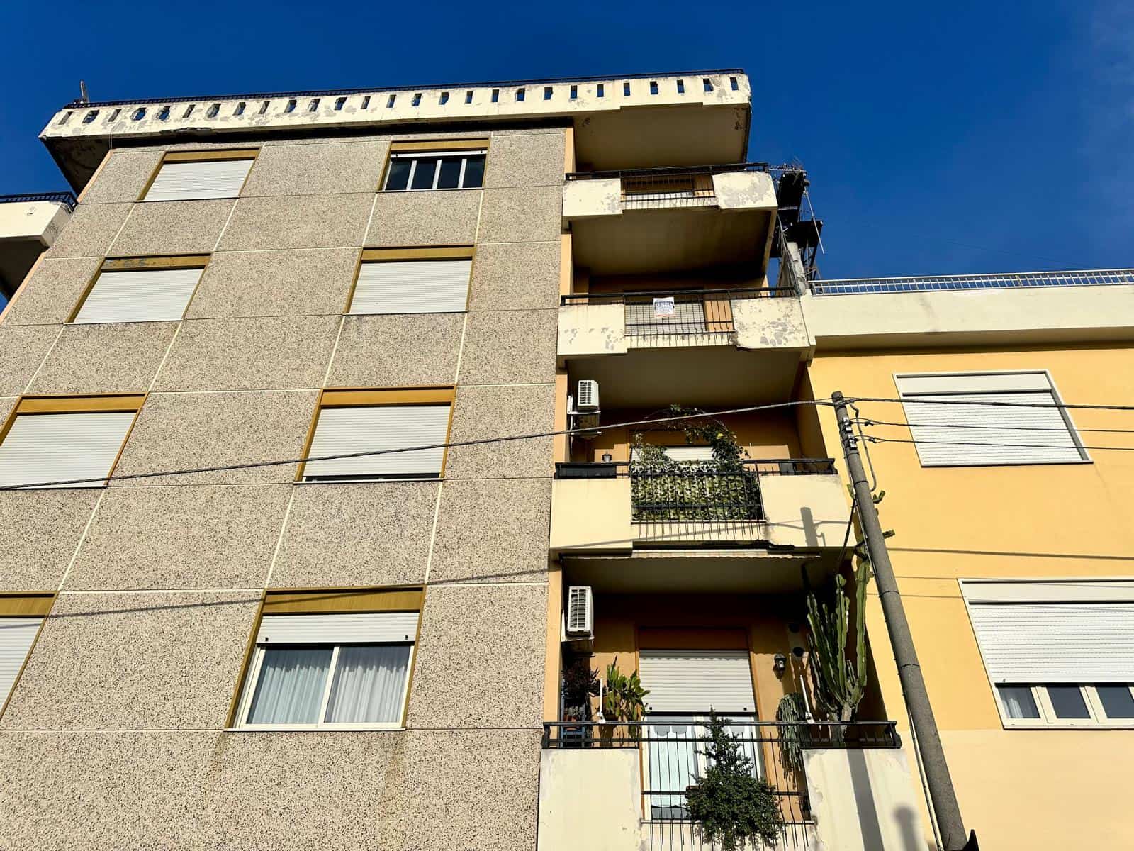 Edificio residenziale con balconi e piante, vista dall'angolo, in una giornata soleggiata, con cielo blu, a NextCasa.