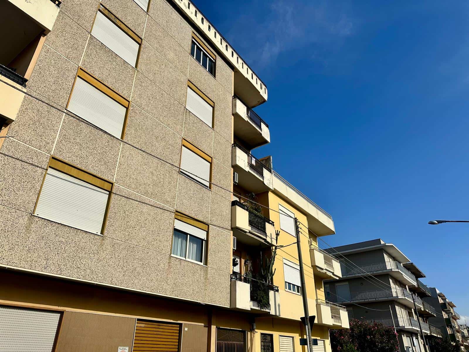 Appartamento moderno con balconi e grandi finestre in edificio residenziale a Milano, Italia, sotto un cielo sereno.