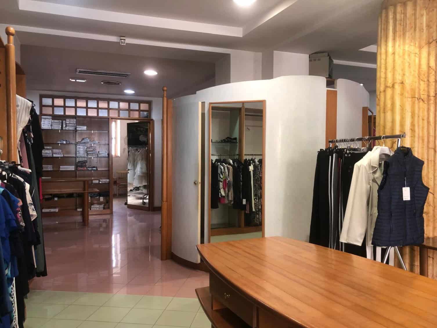 Ampia area di negozio di abbigliamento con scaffali e manichini, ambiente luminoso e accogliente, ideale per boutique di moda e negozi di abbigliamento di alta qualità.