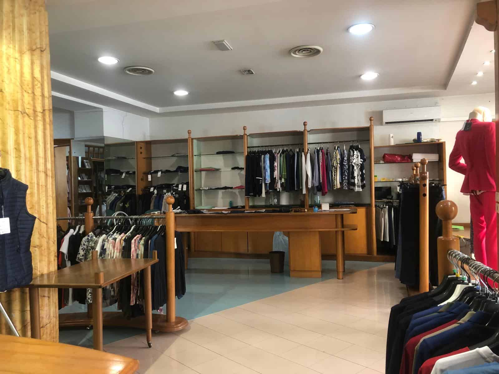 Vestito elegante e casual in negozio di abbigliamento con scaffali e manichini, ambiente moderno e ben illuminato, ideale per shopping di moda uomo e donna.