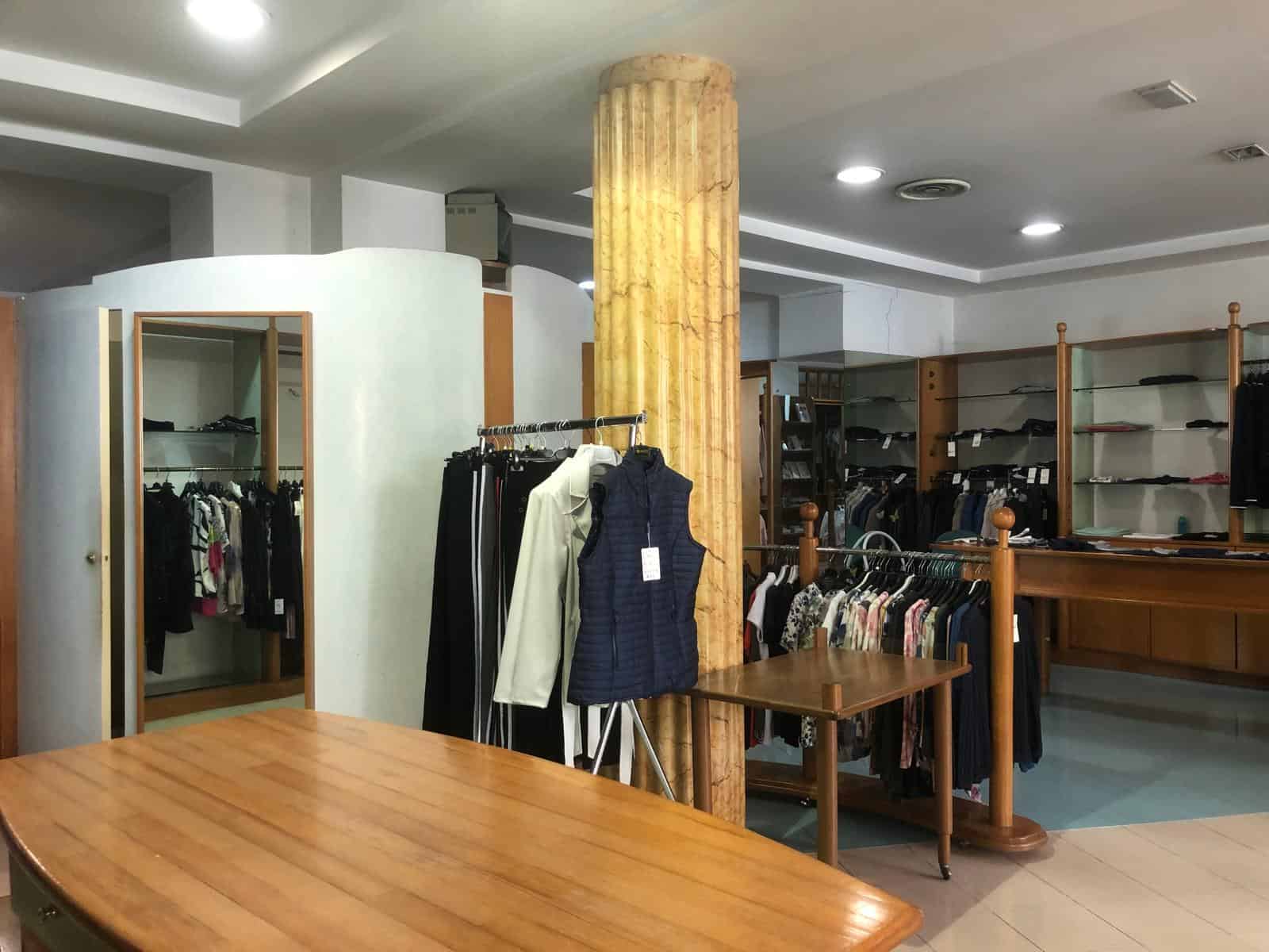 Elegante negozio di abbigliamento con scaffali in legno, vestiti esposti e ambiente accogliente, ideale per shopping di moda e stile.