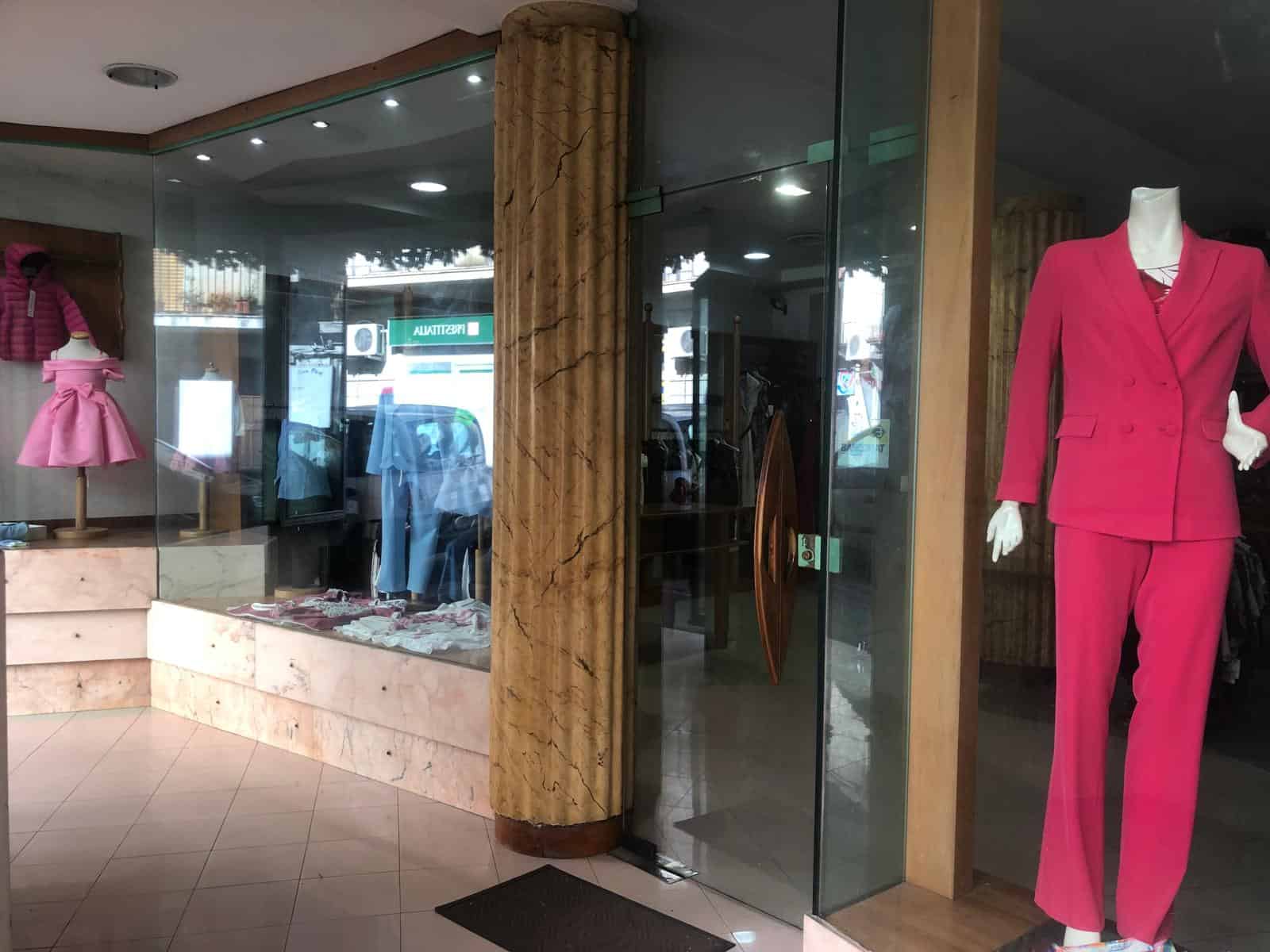 Elegante negozio di abbigliamento con vetrina in vetro, mostra vestiti femminili e un manichino con completo rosa. Ideale per moda donna, boutique di abbigliamento e shopping di stile.