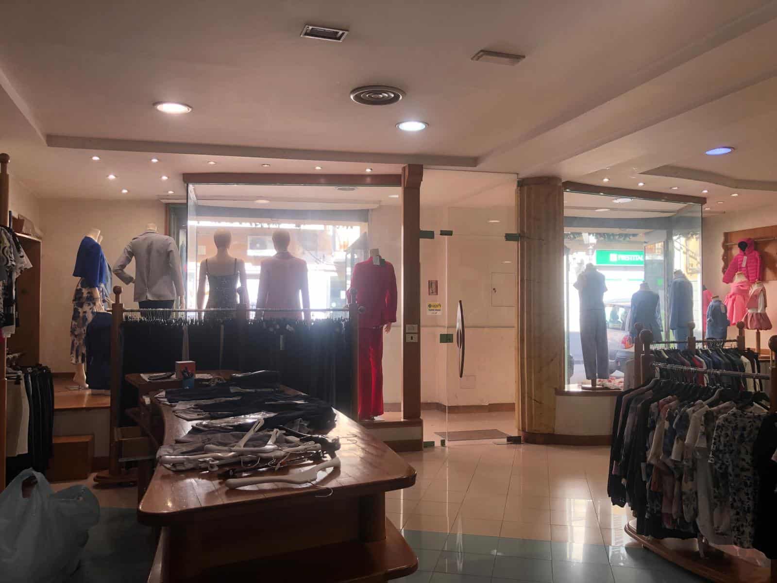Vestiti in vendita in un negozio di abbigliamento con manichini e scaffali pieni di capi di abbigliamento, ambiente luminoso e accogliente, ideale per shopping di moda femminile e maschile.