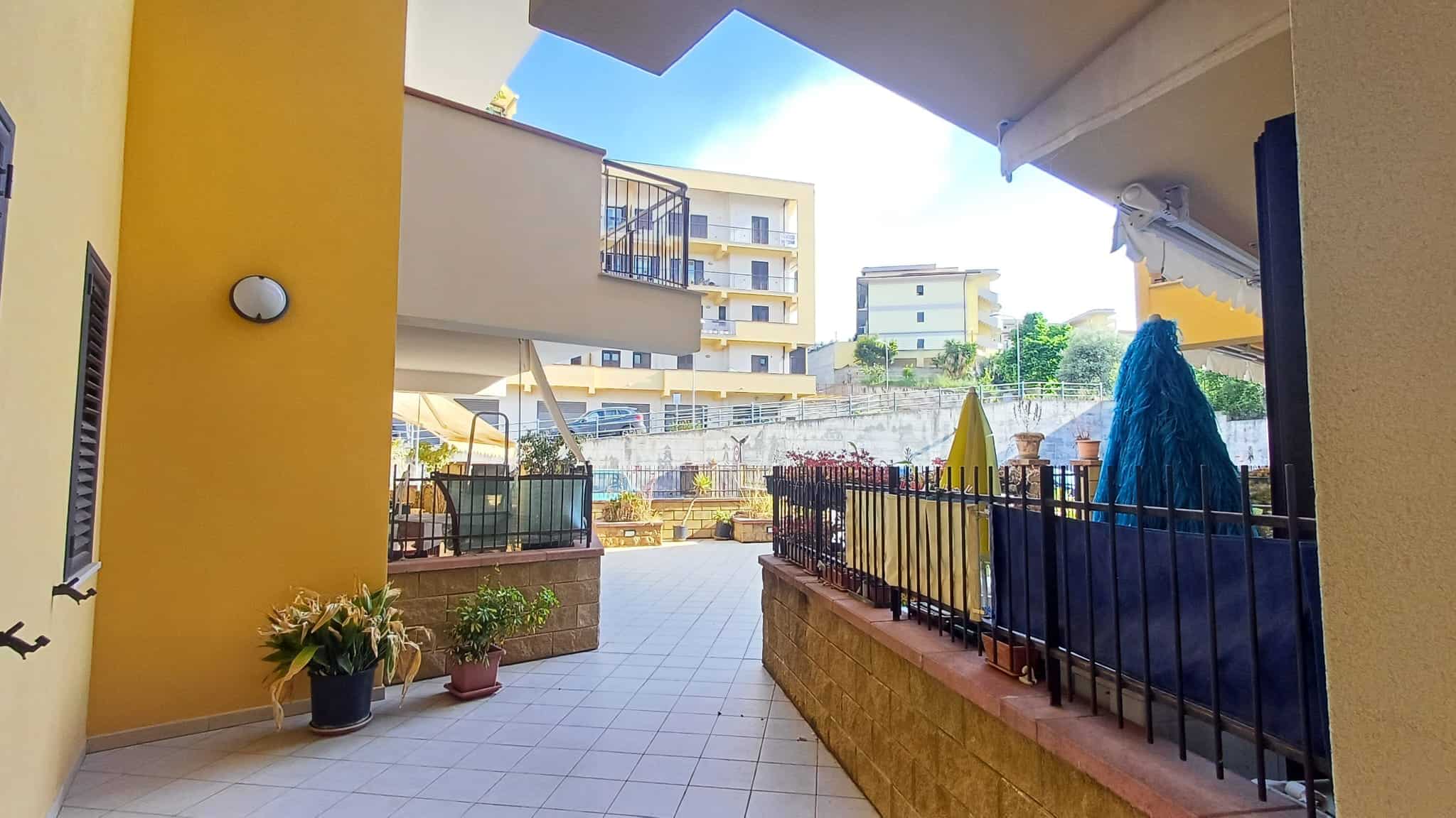 Balcone di un appartamento con vista su complesso residenziale, con piante e arredi esterni, in un ambiente luminoso e accogliente, ideale per relax e momenti all'aperto.