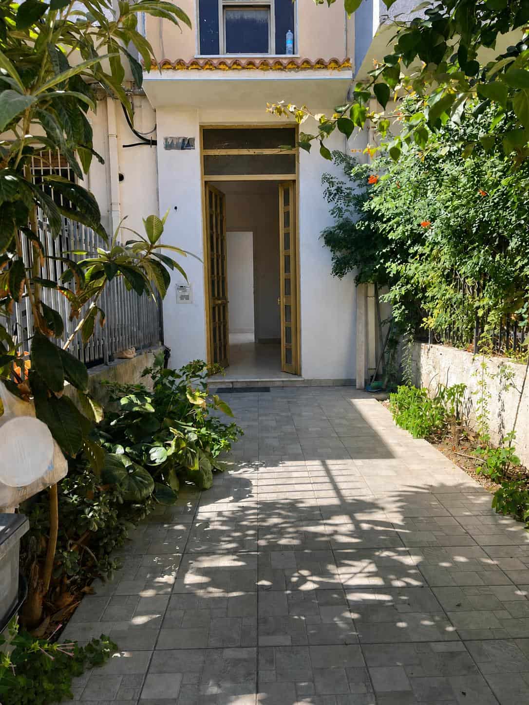 Porte d'ingresso in stile classico con dettagli in legno e vetro, circondata da un giardino verdeggiante e fiorito, in un'abitazione luminosa e accogliente.