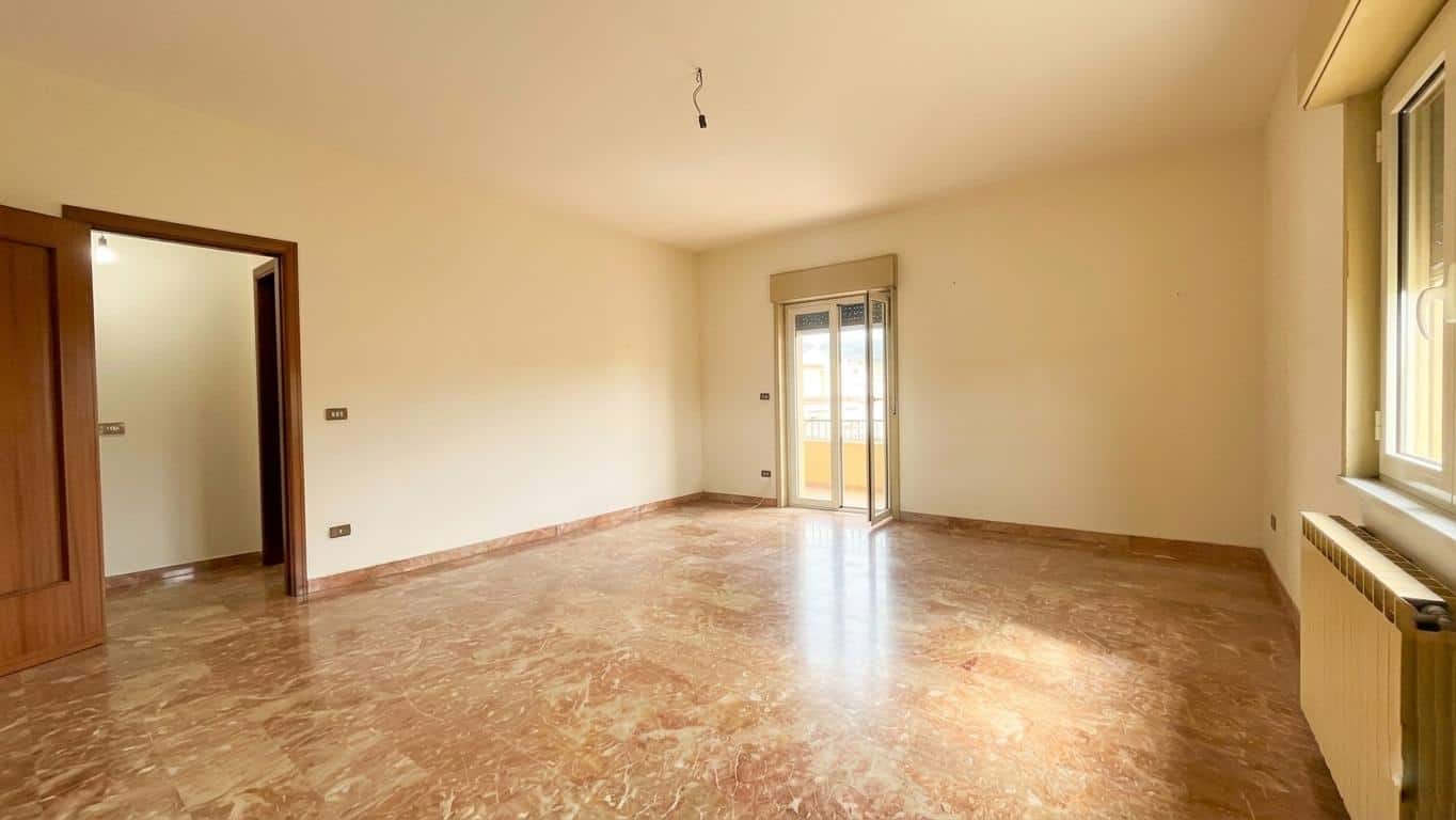 Ampia stanza luminosa con pavimento in marmo, pareti neutre e grandi finestre che offrono luce naturale, ideale per residenze moderne e personalizzabili.