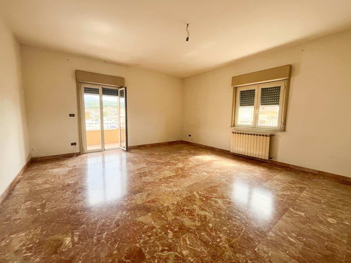 Ampio soggiorno luminoso con pavimenti in marmo, grandi finestre e accesso al balcone, ideale per vivere e rilassarsi in un ambiente elegante e confortevole.