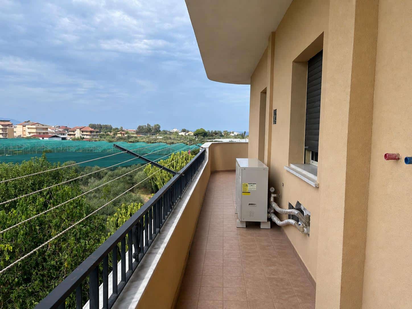 Balcone di un appartamento con vista su aree verdi e cielo sereno, ideale per relax e svago.