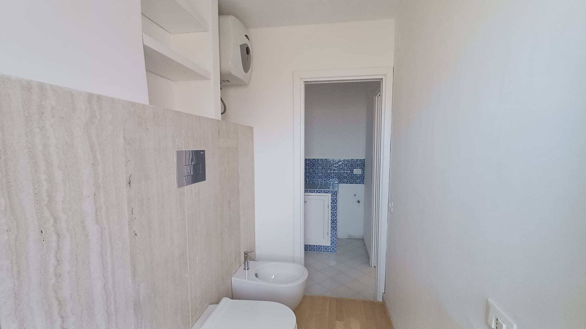 Pannello di controllo del bagno con bidet e porta aperta verso la stanza con piastrelle blu.