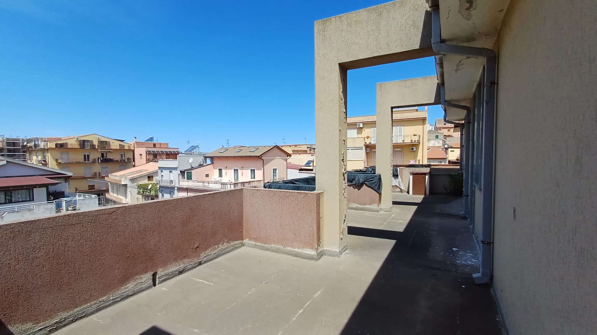 Ampio terrazzo con vista urbana, ideale per relax e socializzazione, in un complesso residenziale a NextCasa, con esposizione soleggiata e spazio per arredi esterni.