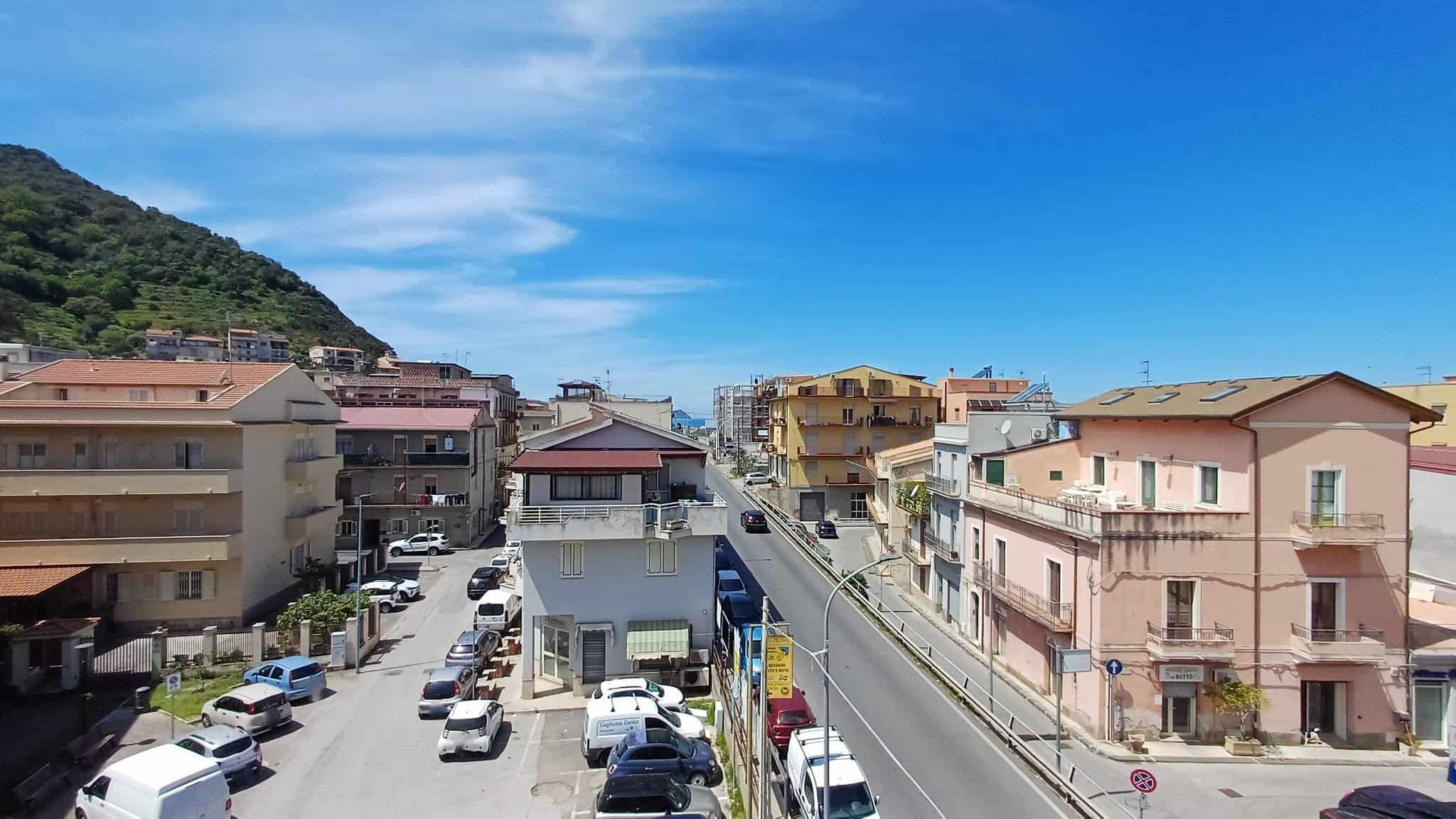 Vista panoramica di un quartiere residenziale con edifici colorati e strade trafficate sotto un cielo sereno e azzurro.