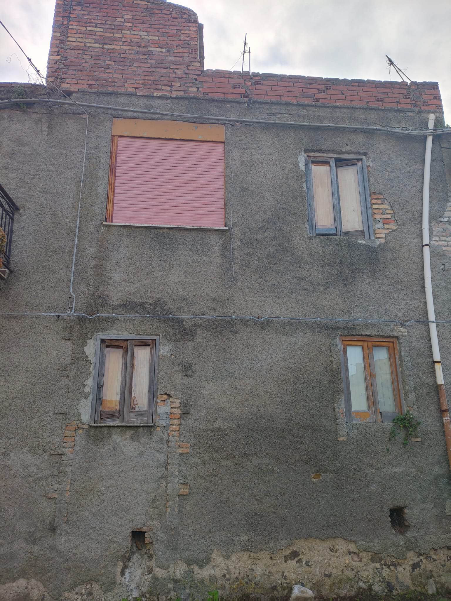Pannello solare installato sul tetto di un edificio residenziale con pareti in cemento e finestre in legno, evidenziando l'efficienza energetica e il risparmio energetico.